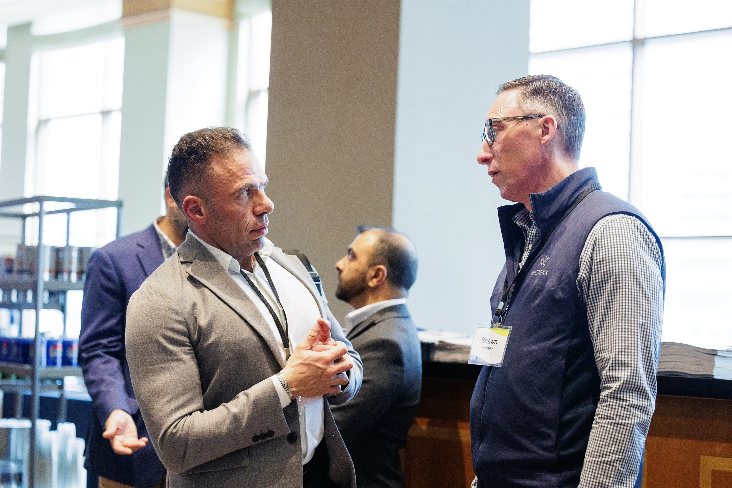 Two attendees in conversation near tall windows during networking break at Chicago corporate event