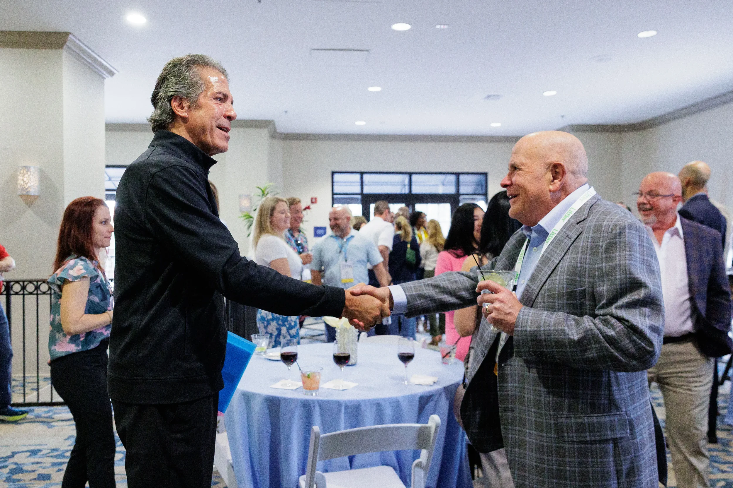 Two attendees shake hands and smile during cocktail reception at Chicago corporate conference