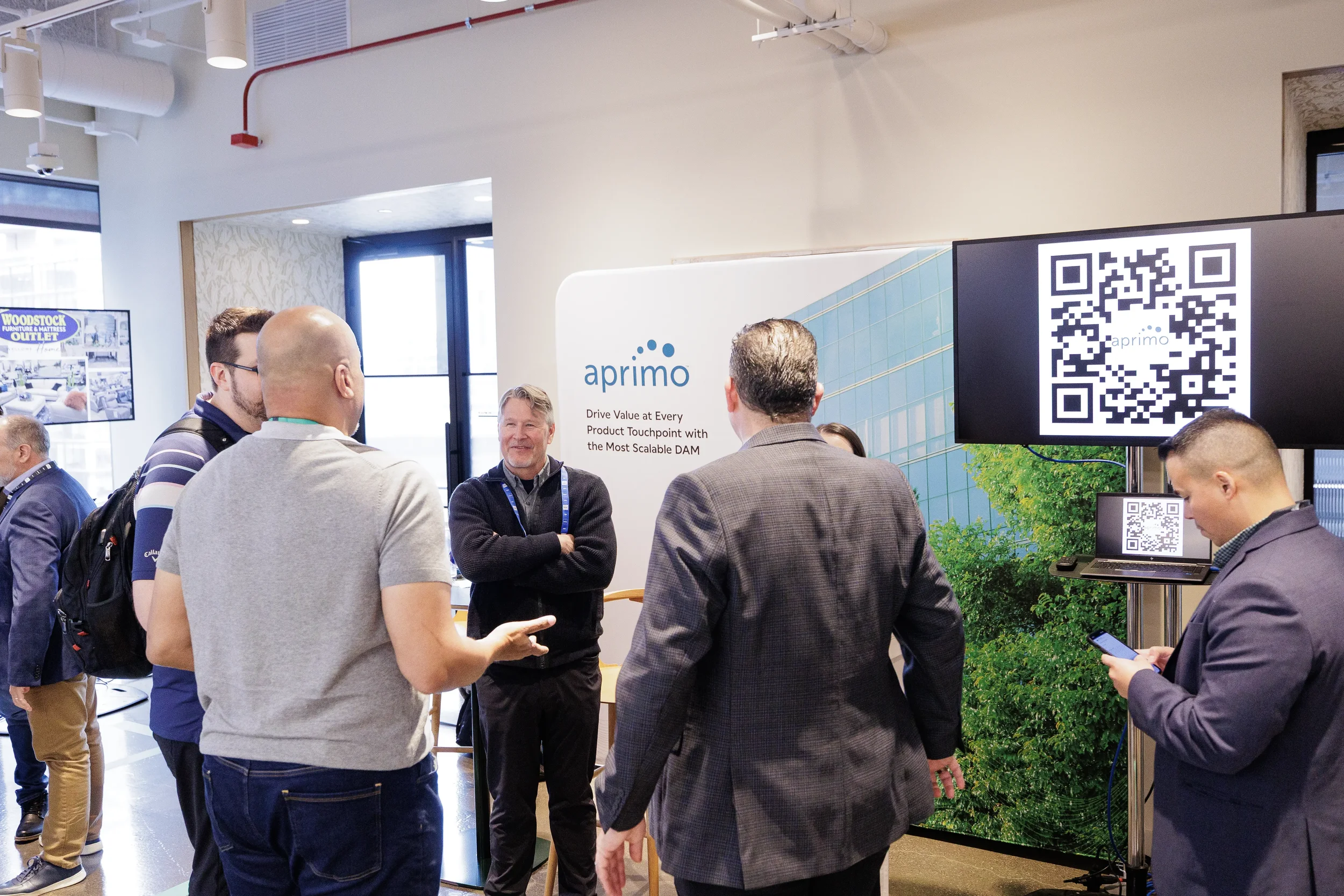 Attendees talk with exhibitor at booth with QR code display during Orlando corporate trade show