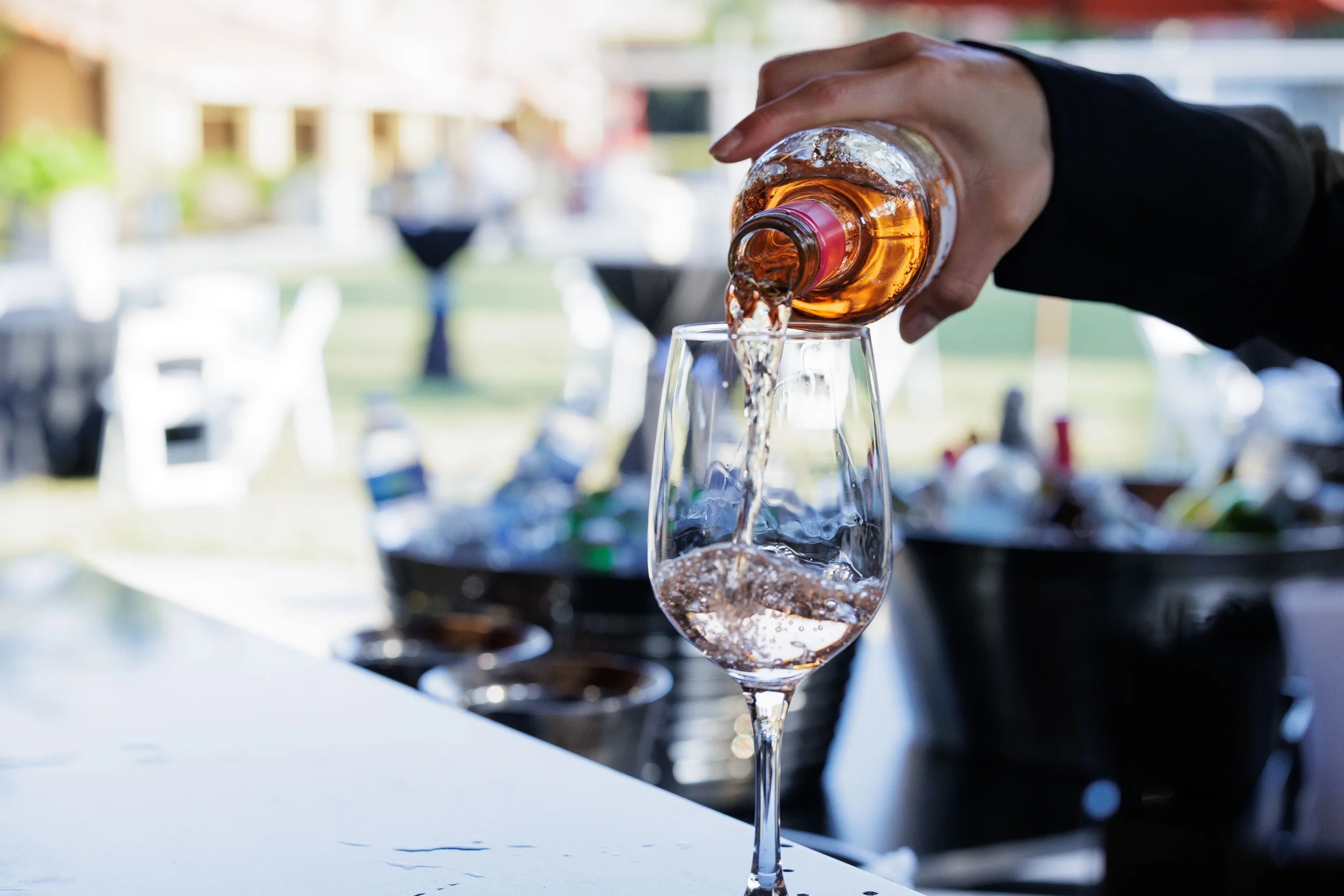 Bartender pours rosé wine into glass at outdoor bar during Chicago corporate conference reception