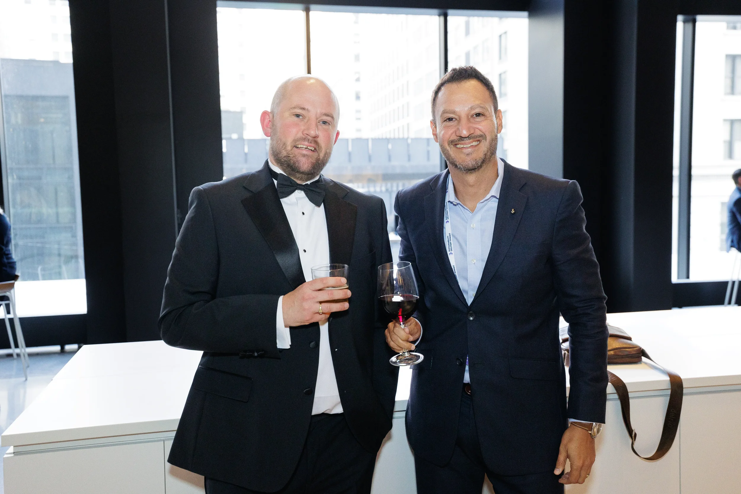 Two attendees in formal attire smile while holding wine glasses at Orlando corporate conference