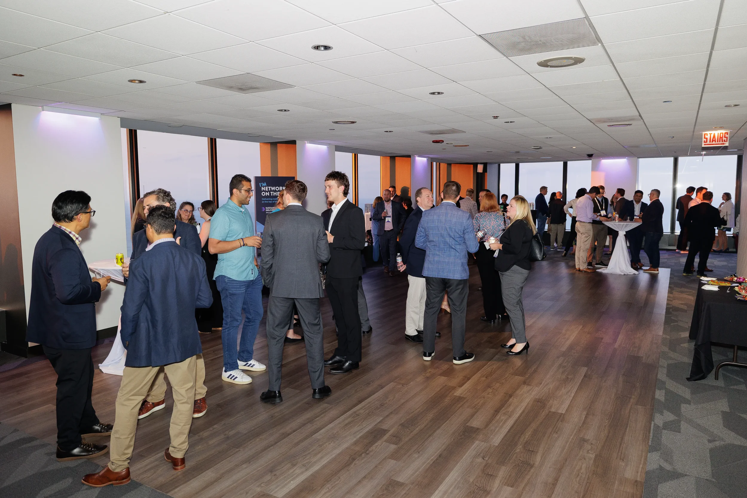 Attendees network during evening reception with skyline views at Chicago corporate summit