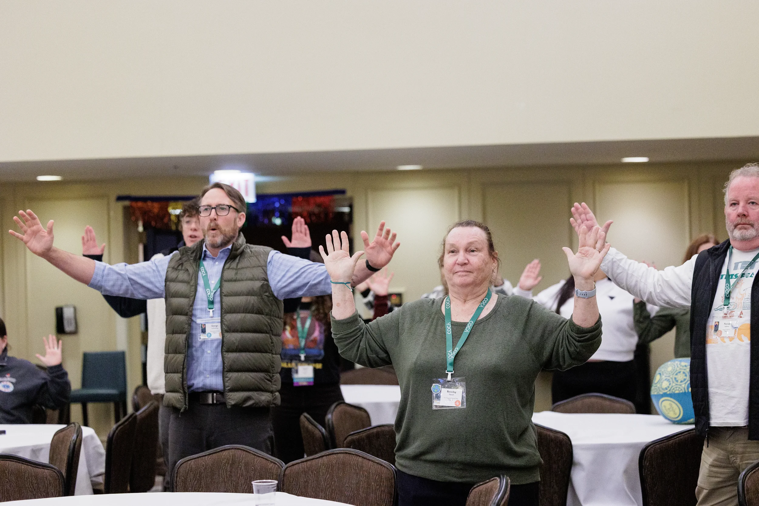 Attendees raise hands during energetic group activity in ballroom at Chicago nonprofit conference event