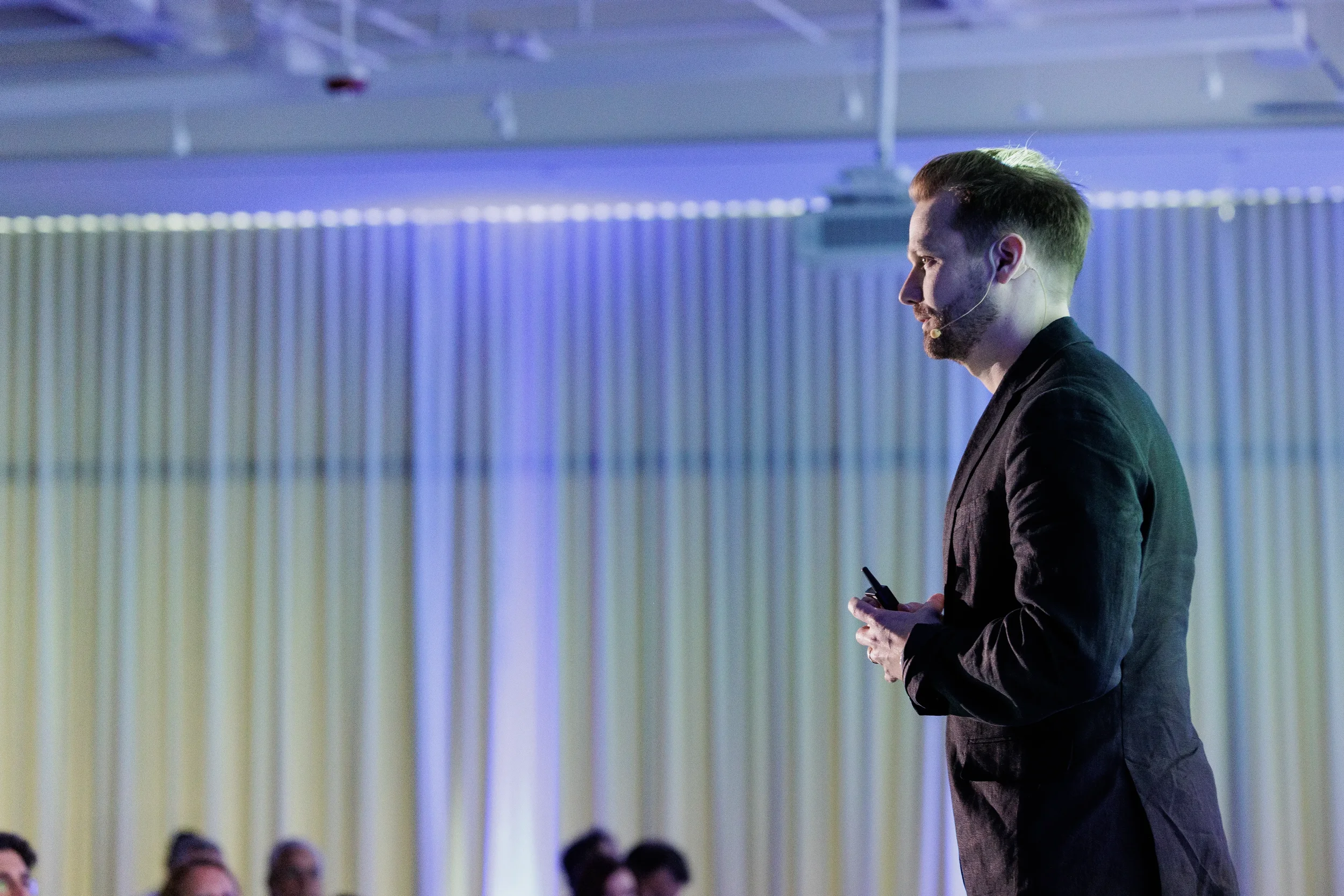 Speaker in dark blazer with clicker presents in profile against curtain backdrop at Chicago conference