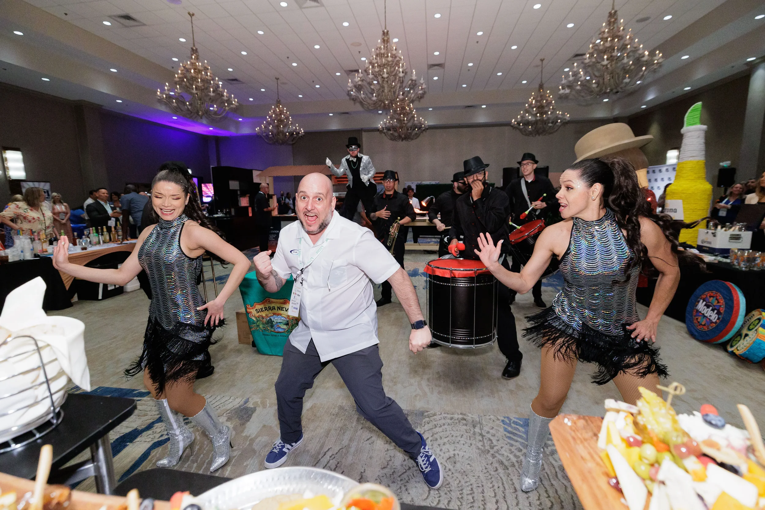 Attendee dances energetically between two fringe-costumed performers with live band at Orlando corporate event