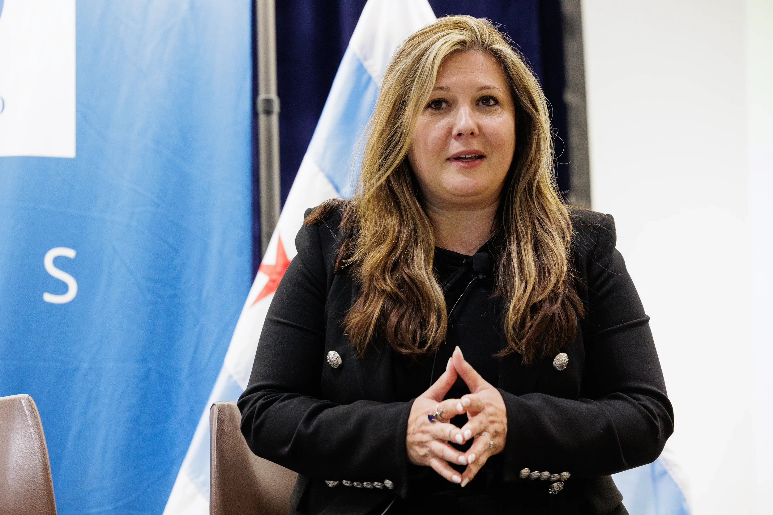 Female panelist seated on stage with Chicago flag and branded backdrop at Chicago industry conference