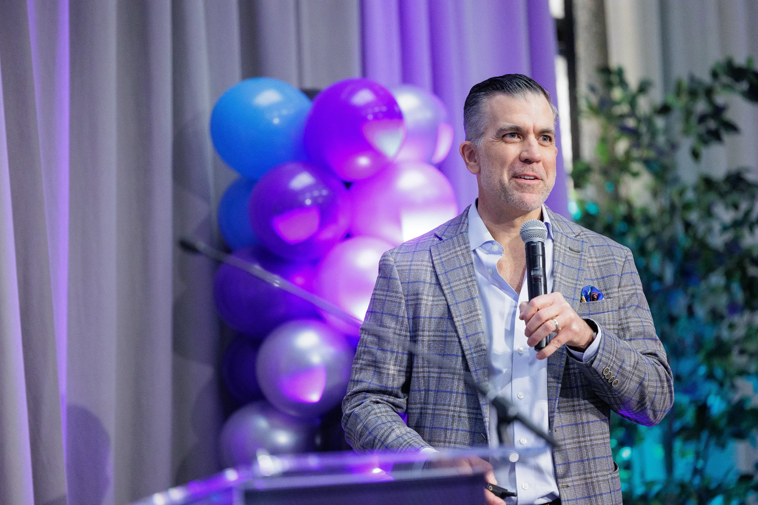 Speaker addresses audience with handheld microphone at podium during Chicago corporate event