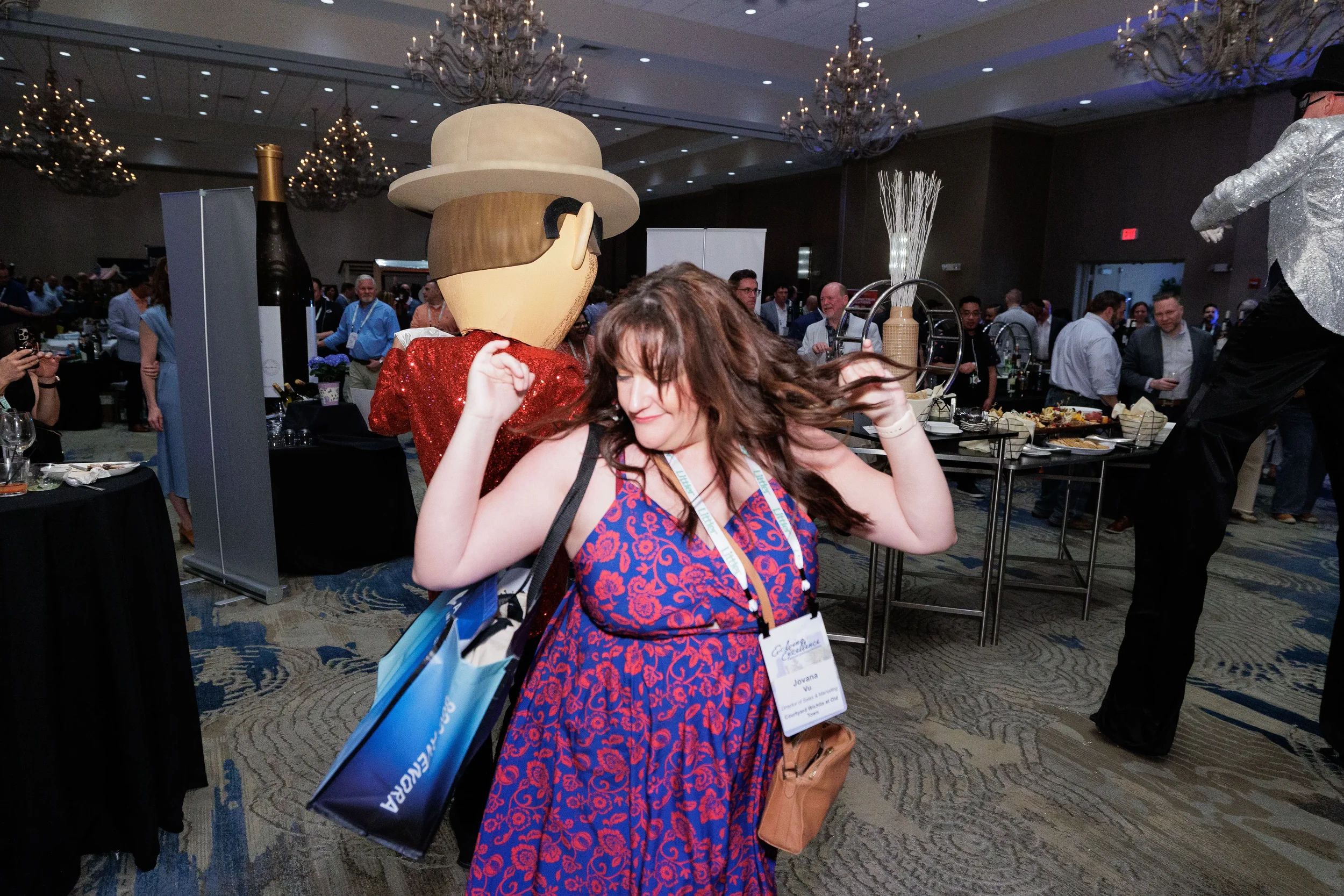 Female attendee dances energetically alongside costumed mascot in chandelier ballroom at Orlando corporate event