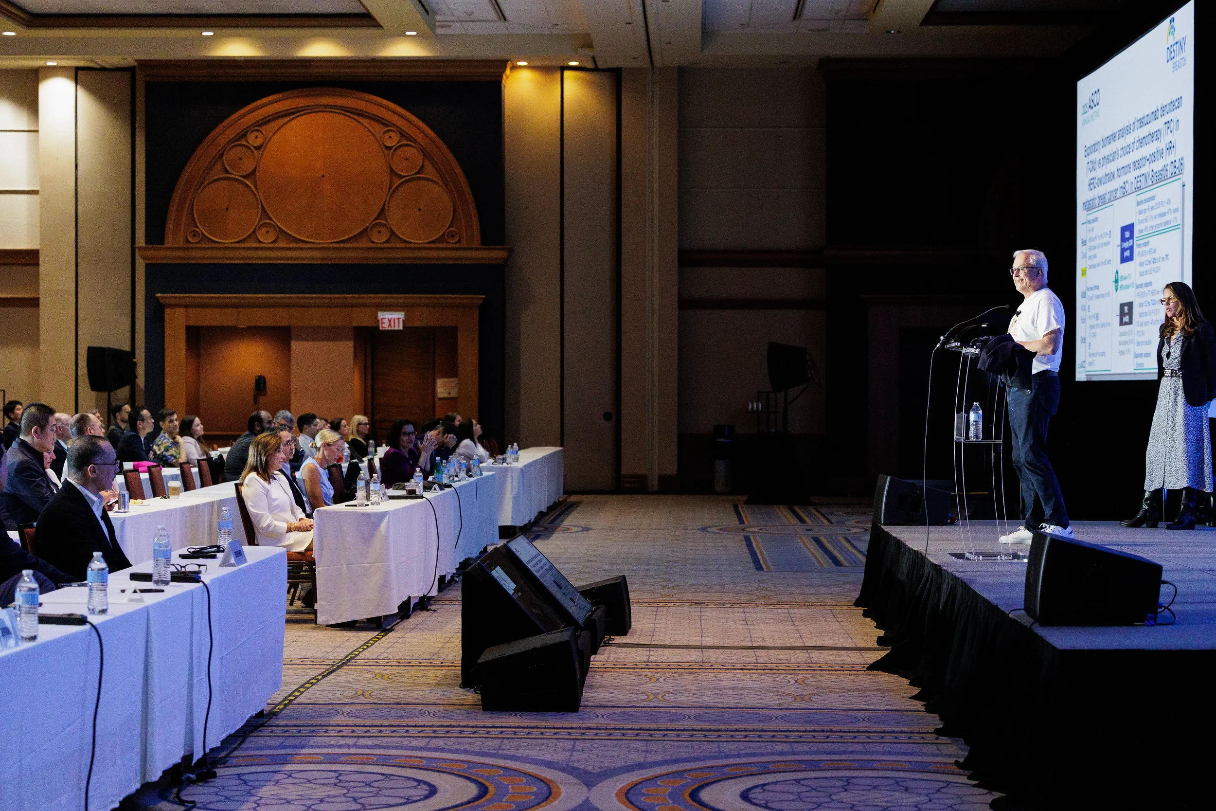 Speaker presents from podium with presentation screen in ballroom at Chicago industry conference