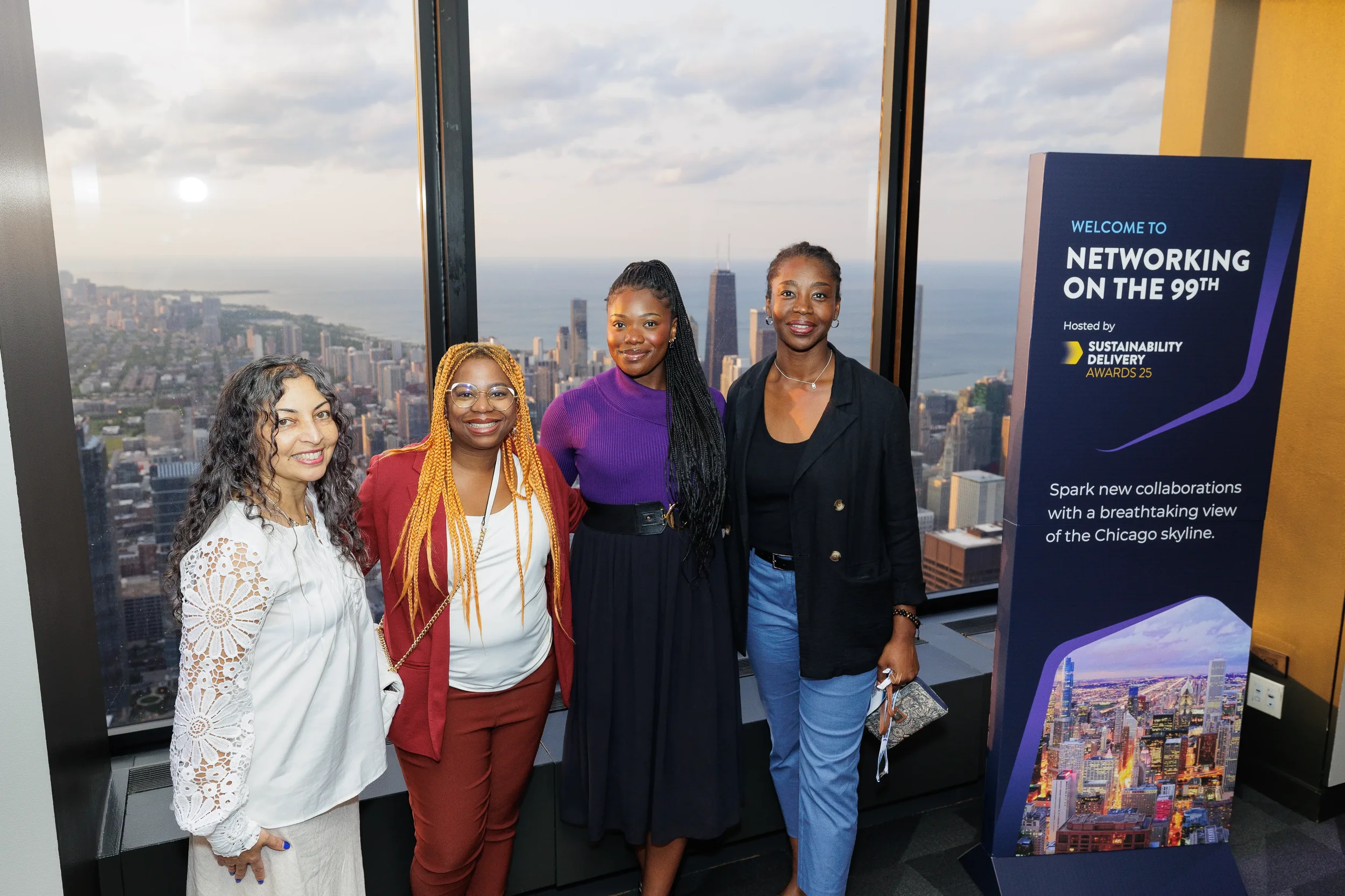 Four attendees pose for group photo at networking reception with Chicago skyline view
