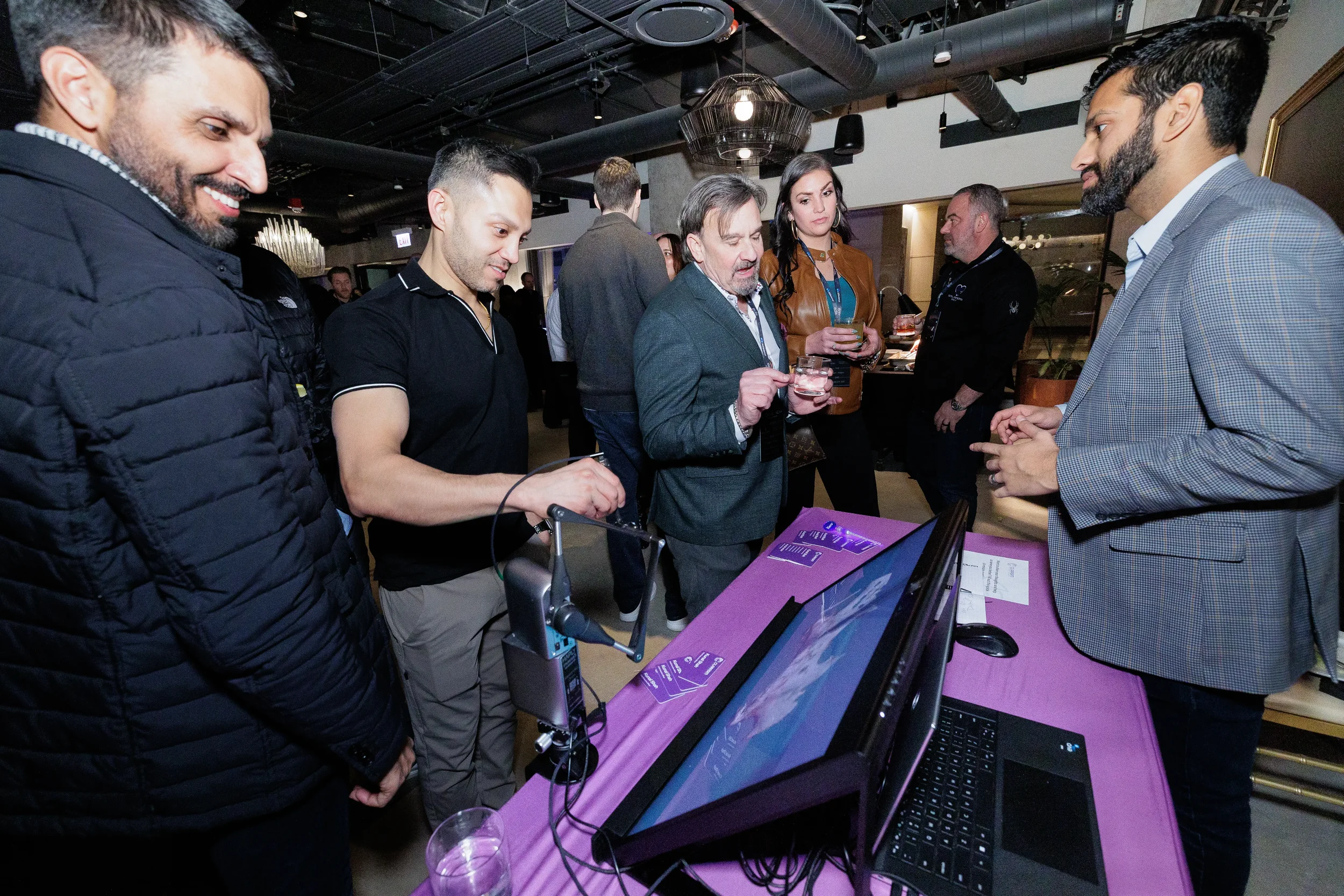 Attendees gather around tech product demonstration table during Orlando corporate event