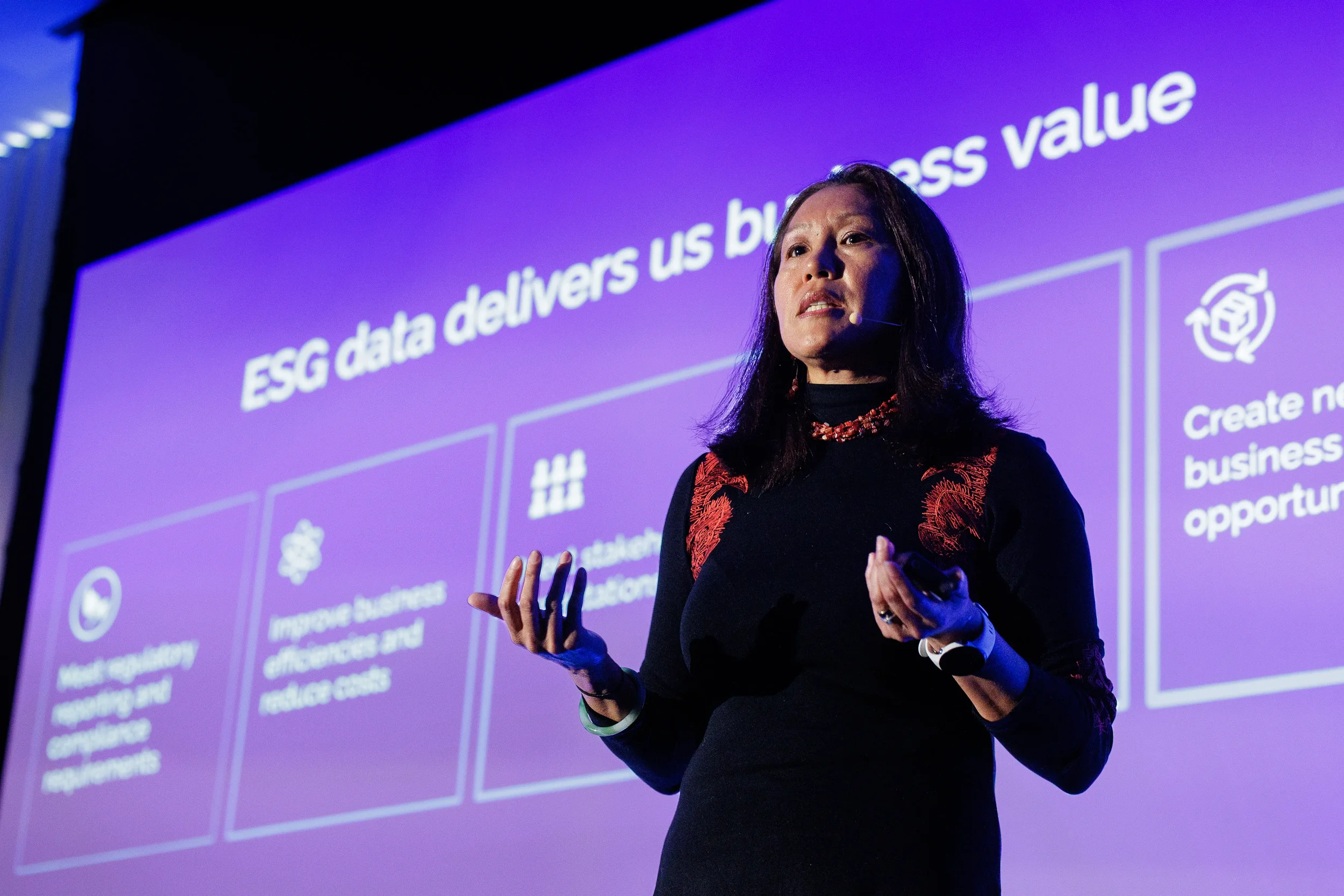 Speaker with headset microphone presents beside purple business value slide at Chicago conference