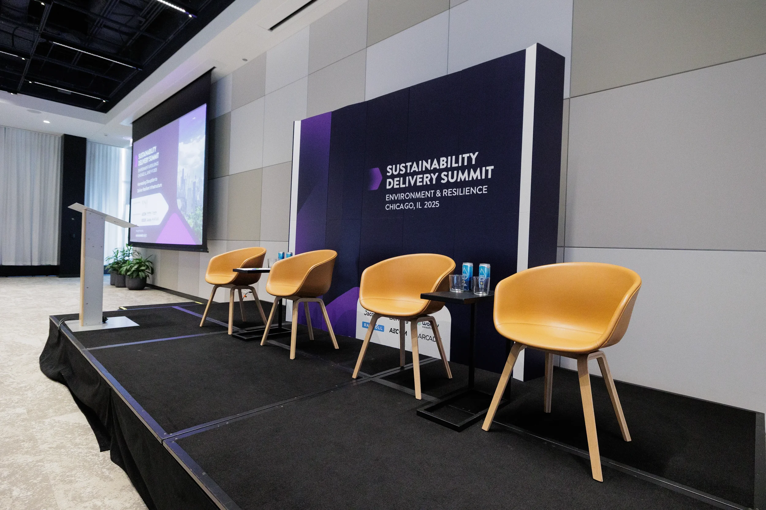 Panel stage set with empty chairs and branded backdrop ahead of Chicago industry summit session