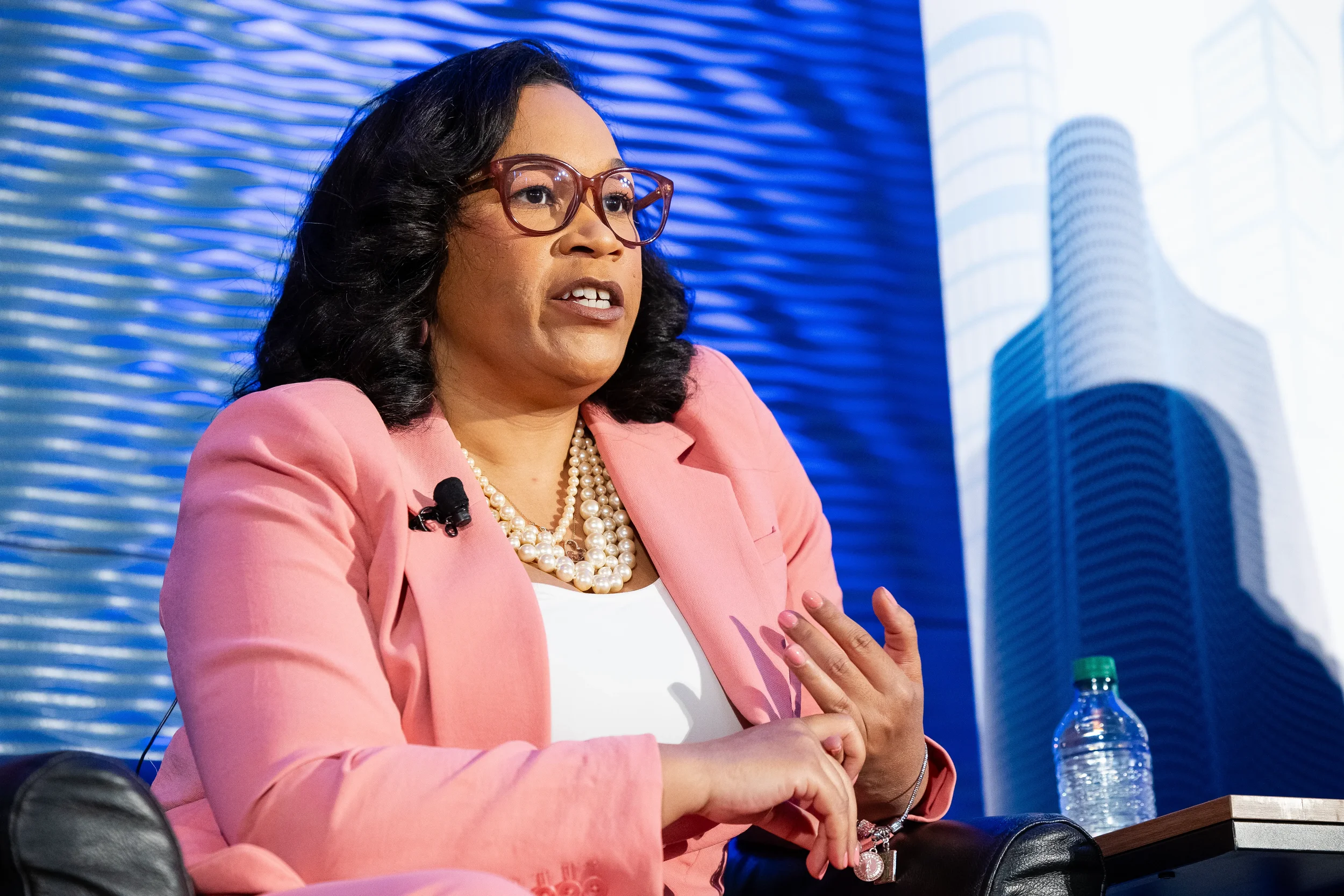 Panelist gestures while speaking on stage with city skyline backdrop at Orlando conference