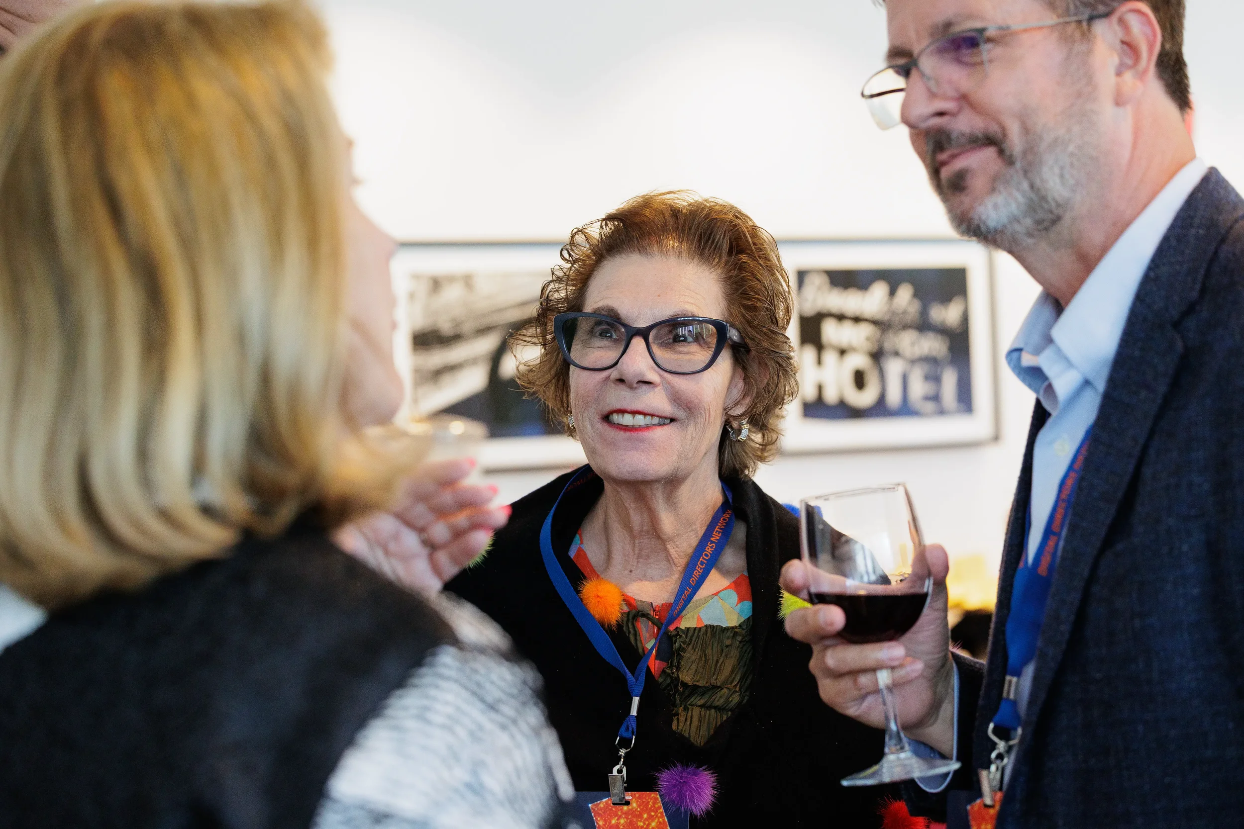 Three attendees with lanyards smile and chat over wine during Orlando corporate conference reception