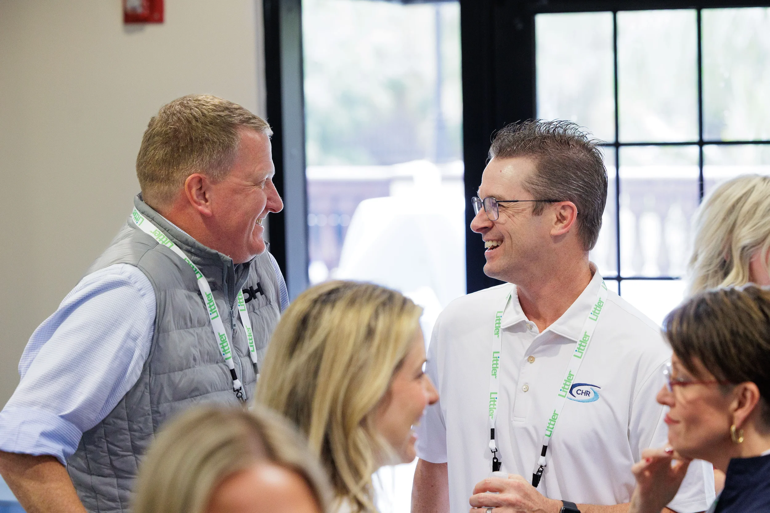 Two male attendees with lanyards laugh together during Chicago corporate conference networking reception