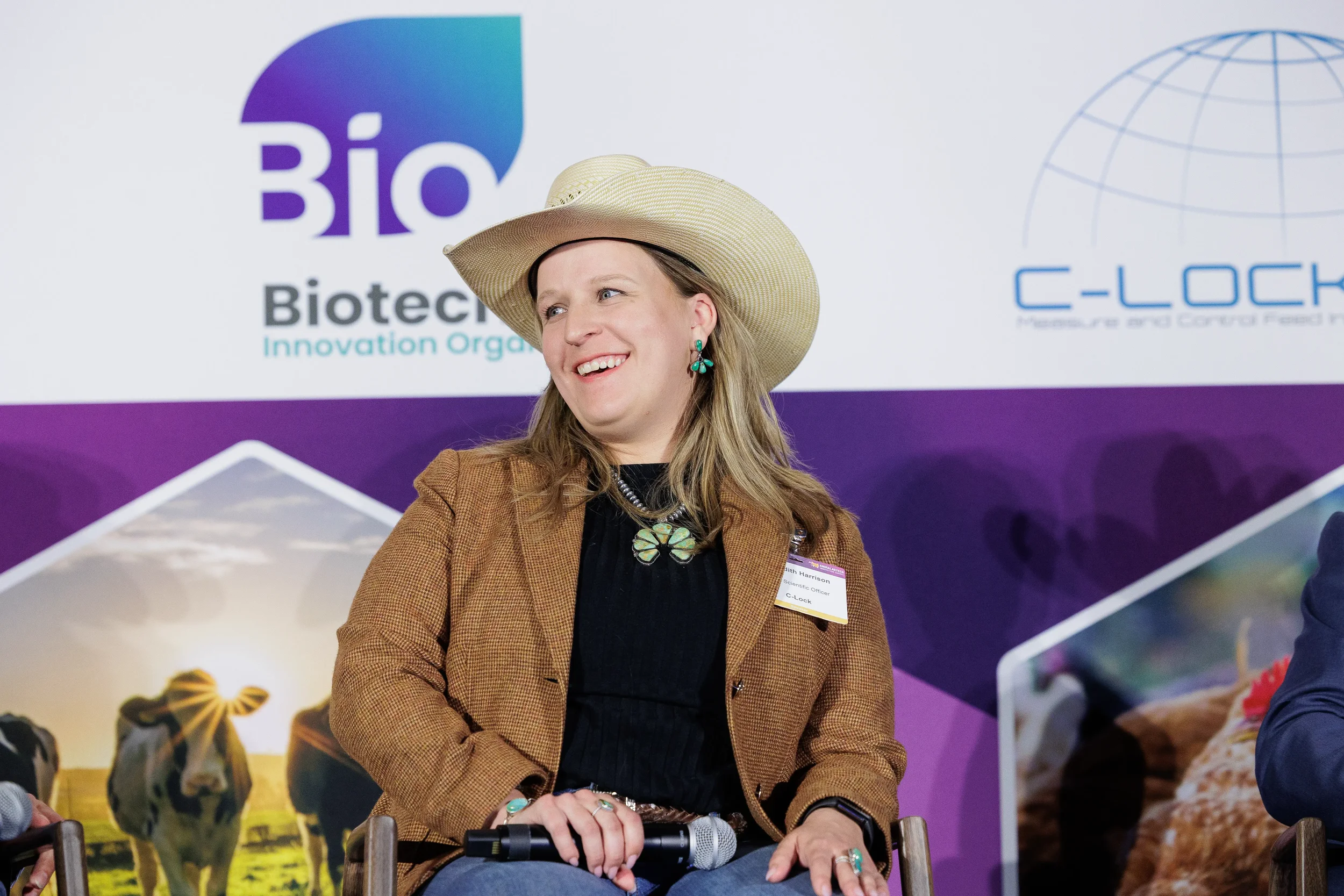 Speaker in cowboy hat smiles on branded stage during session at Chicago industry summit