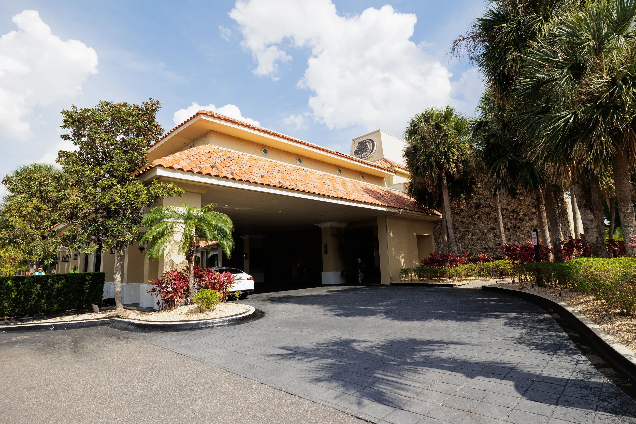 Sunny hotel exterior with palm trees and covered entrance drive at Orlando corporate conference venue