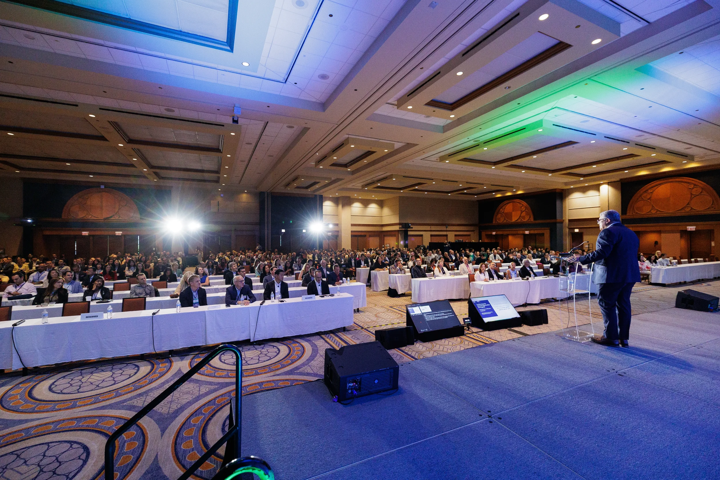 Wide view of speaker addressing seated audience in ballroom at Orlando industry conference