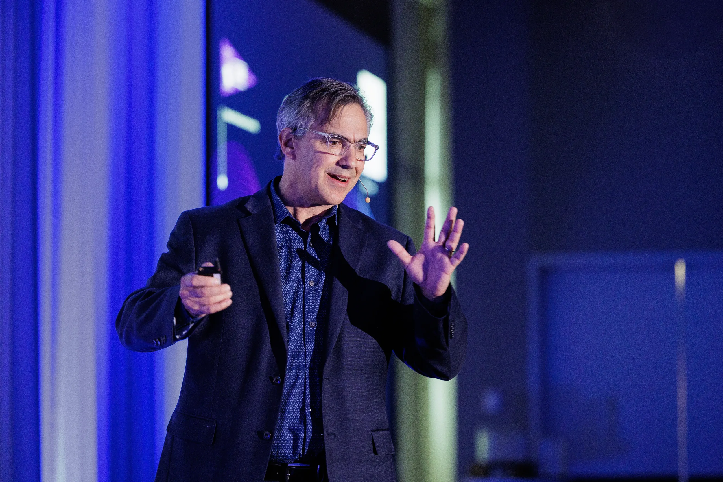Speaker with headset microphone gestures while presenting on stage at Chicago corporate conference