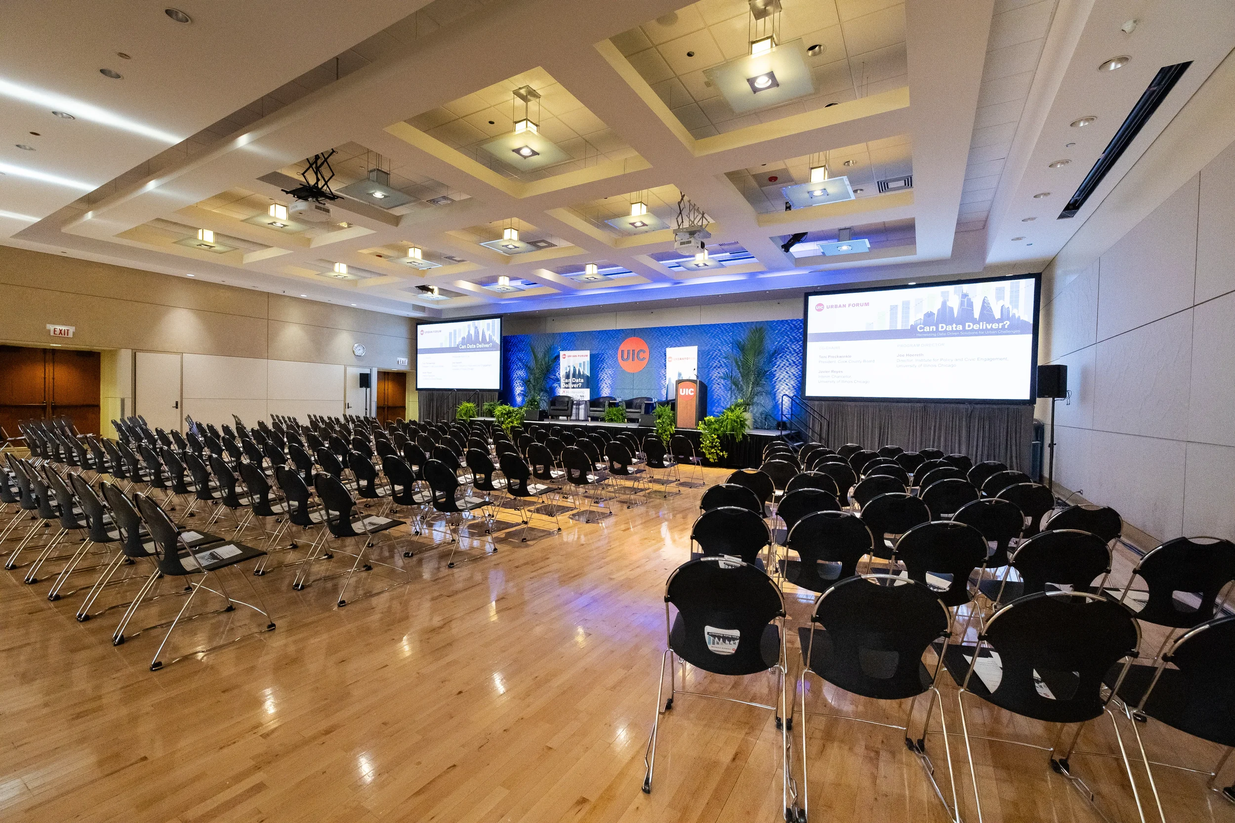Wide view of empty conference hall with rows of chairs facing branded stage at Orlando event