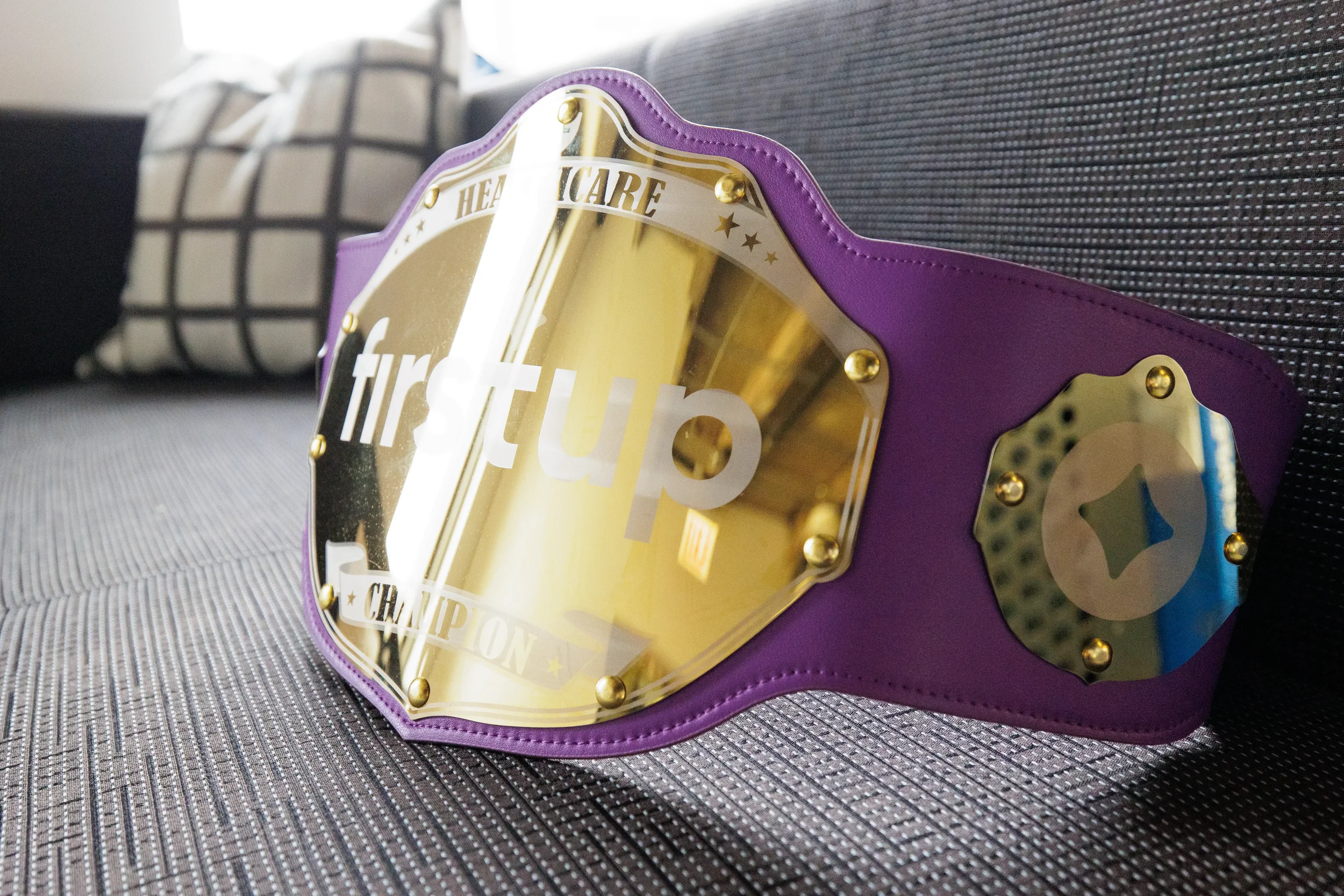 Close-up of branded purple and gold champion belt on couch at Orlando corporate event