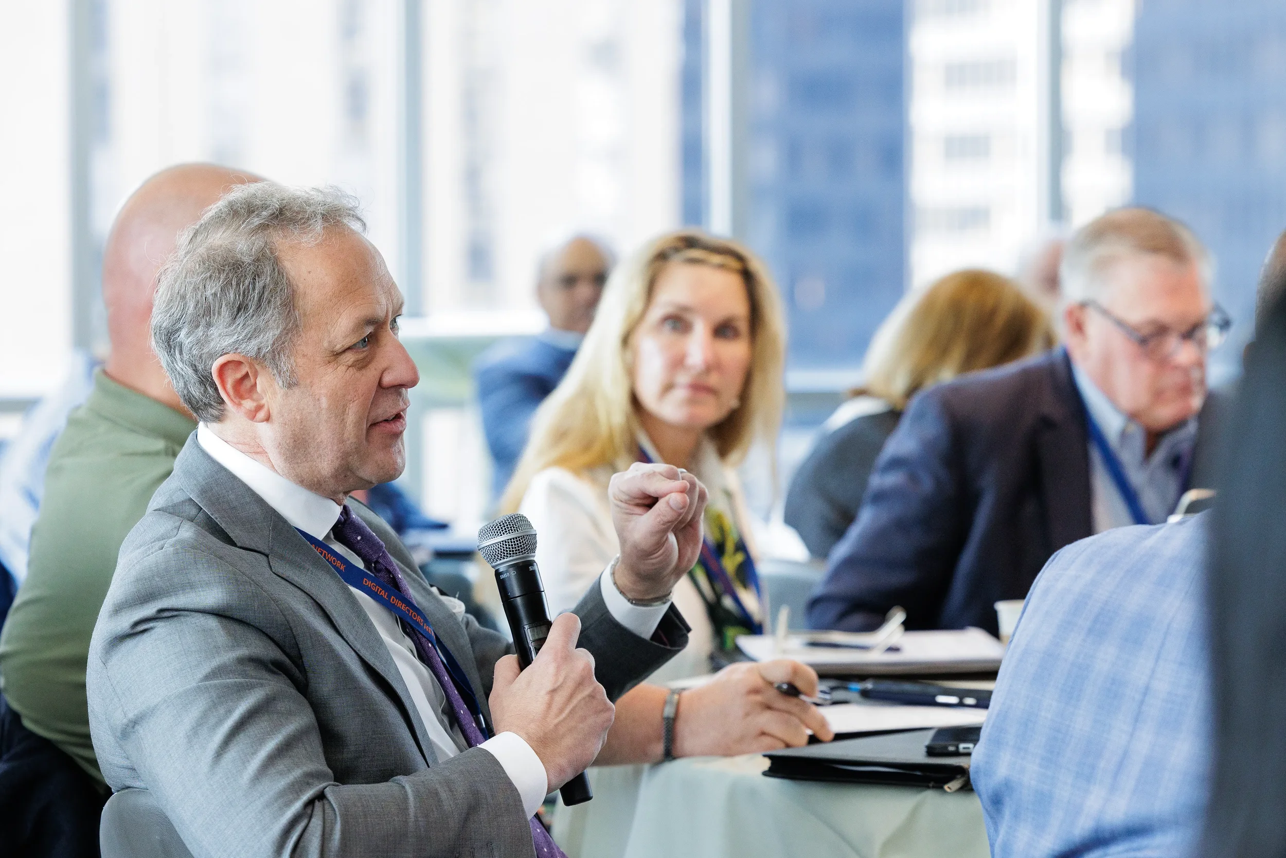 Suited attendee holds microphone while speaking during seated session at Chicago corporate conference