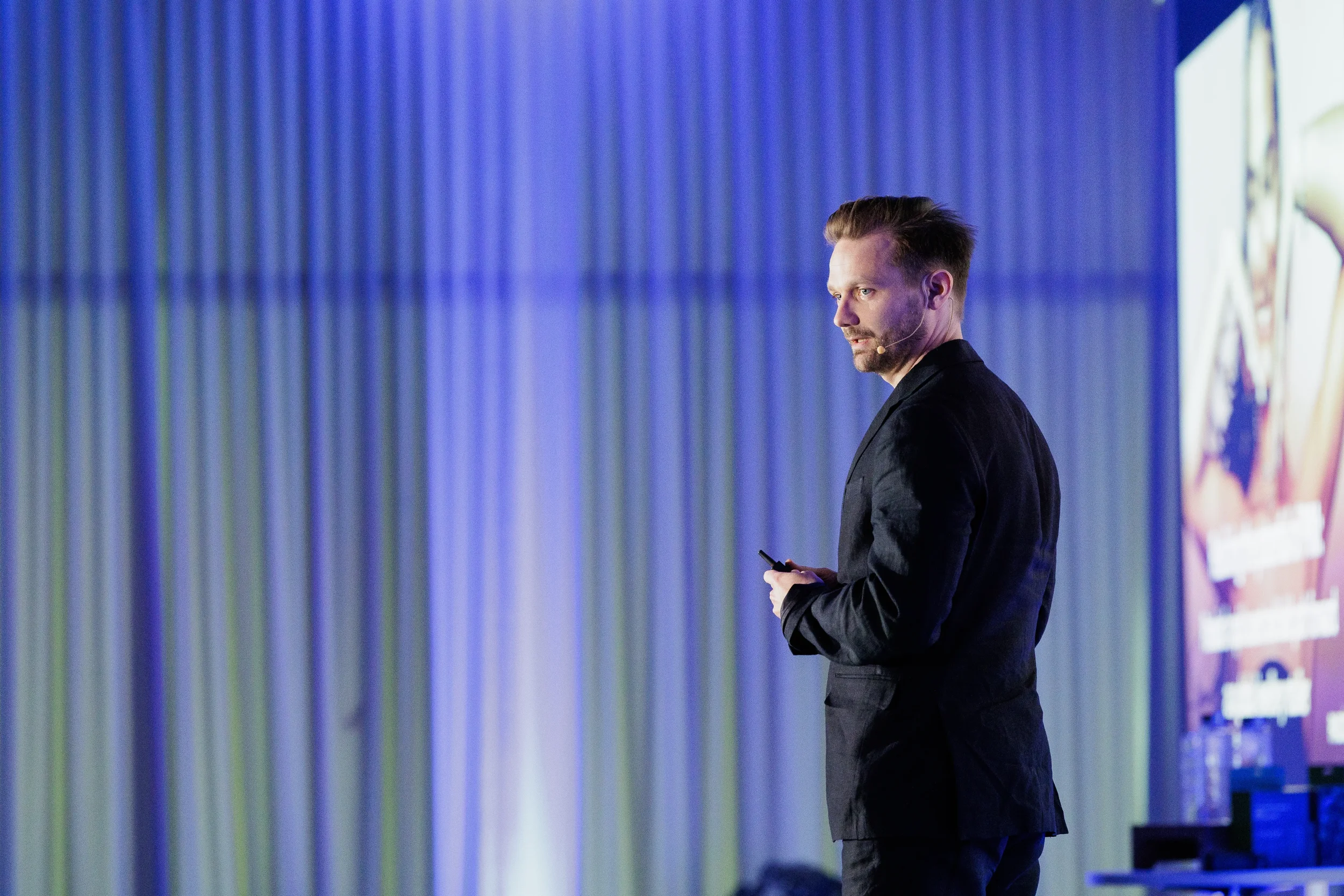 Speaker in dark suit with headset microphone presents on stage at Chicago industry conference