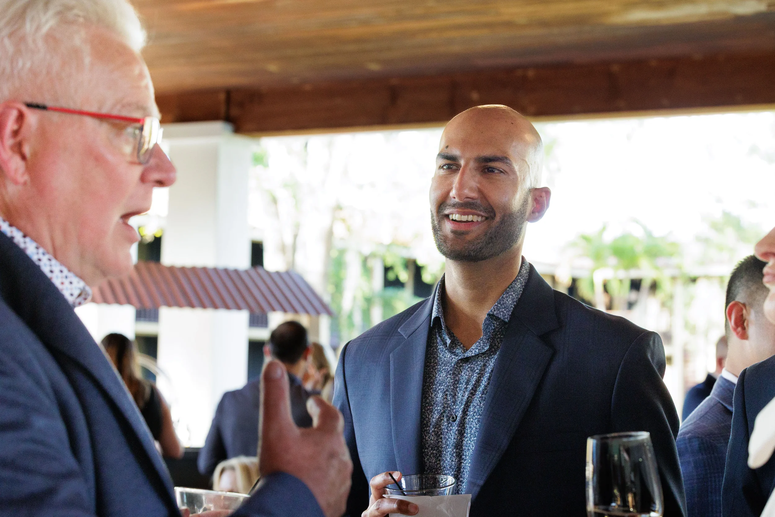 Two attendees smile and converse over drinks under outdoor pavilion at Chicago corporate event