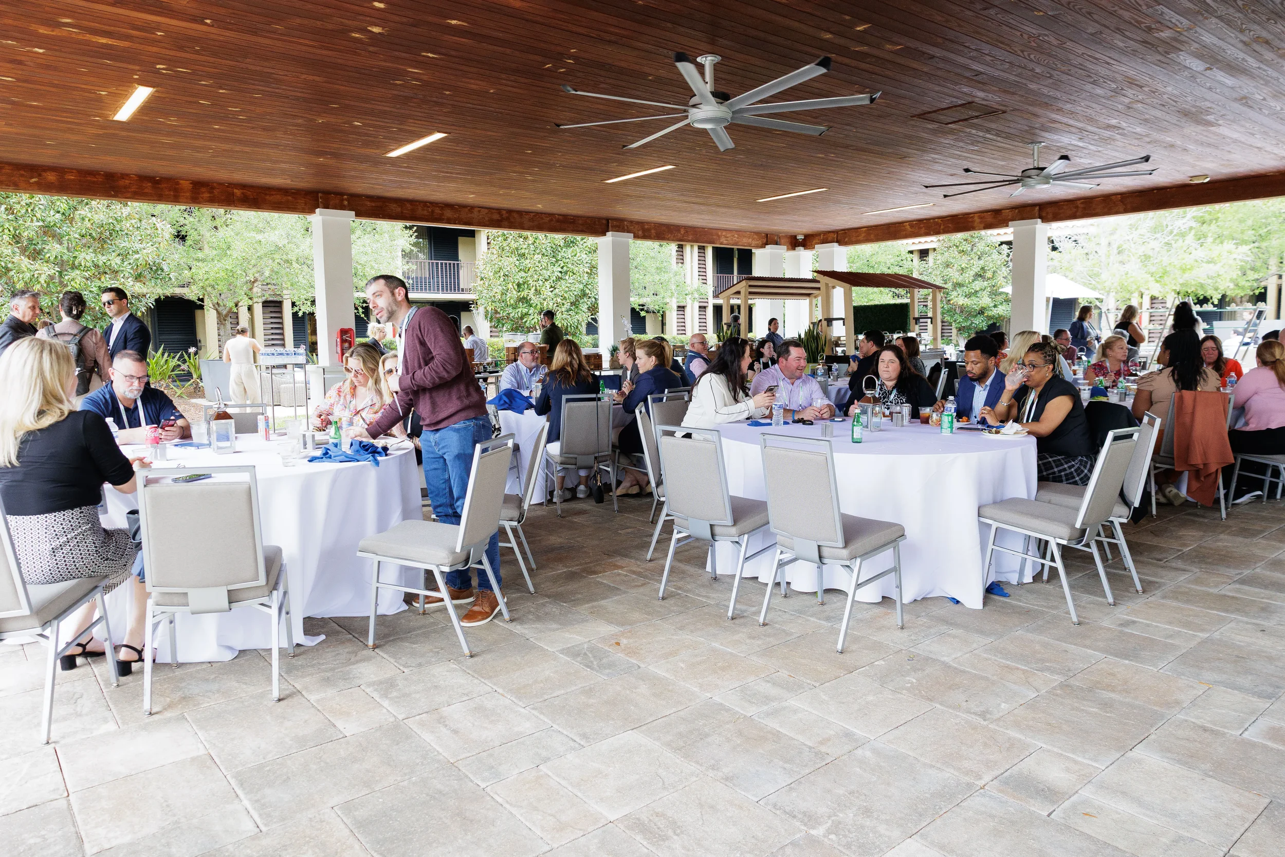 Attendees dine at round tables under covered outdoor pavilion at Chicago corporate conference