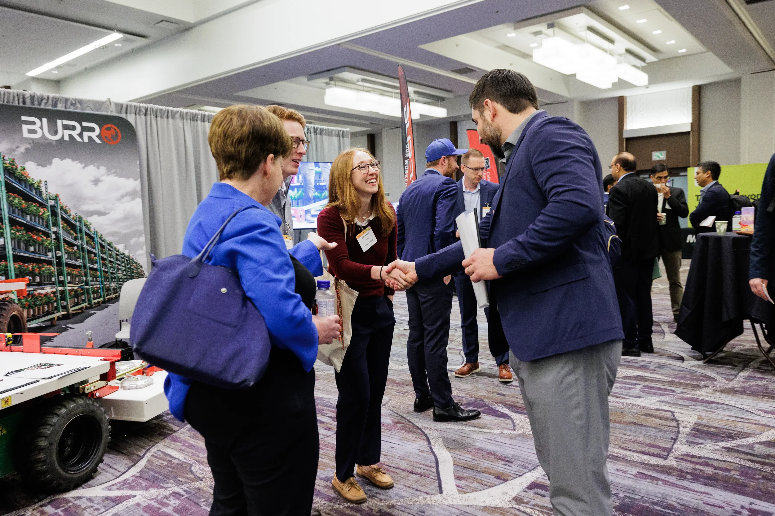 Attendees shake hands while networking near exhibitor booth at Orlando industry conference