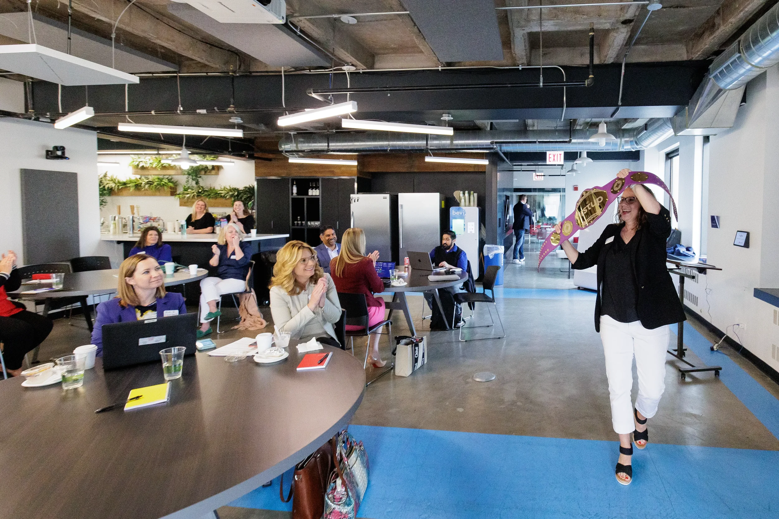 Female attendee parades a branded champion belt through a cheering room at Chicago corporate event