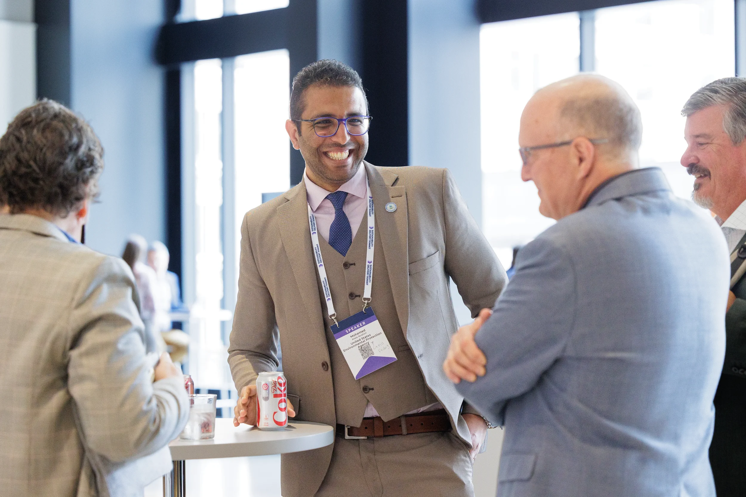 Speaker laughs during conversation at standing table at Orlando corporate conference reception
