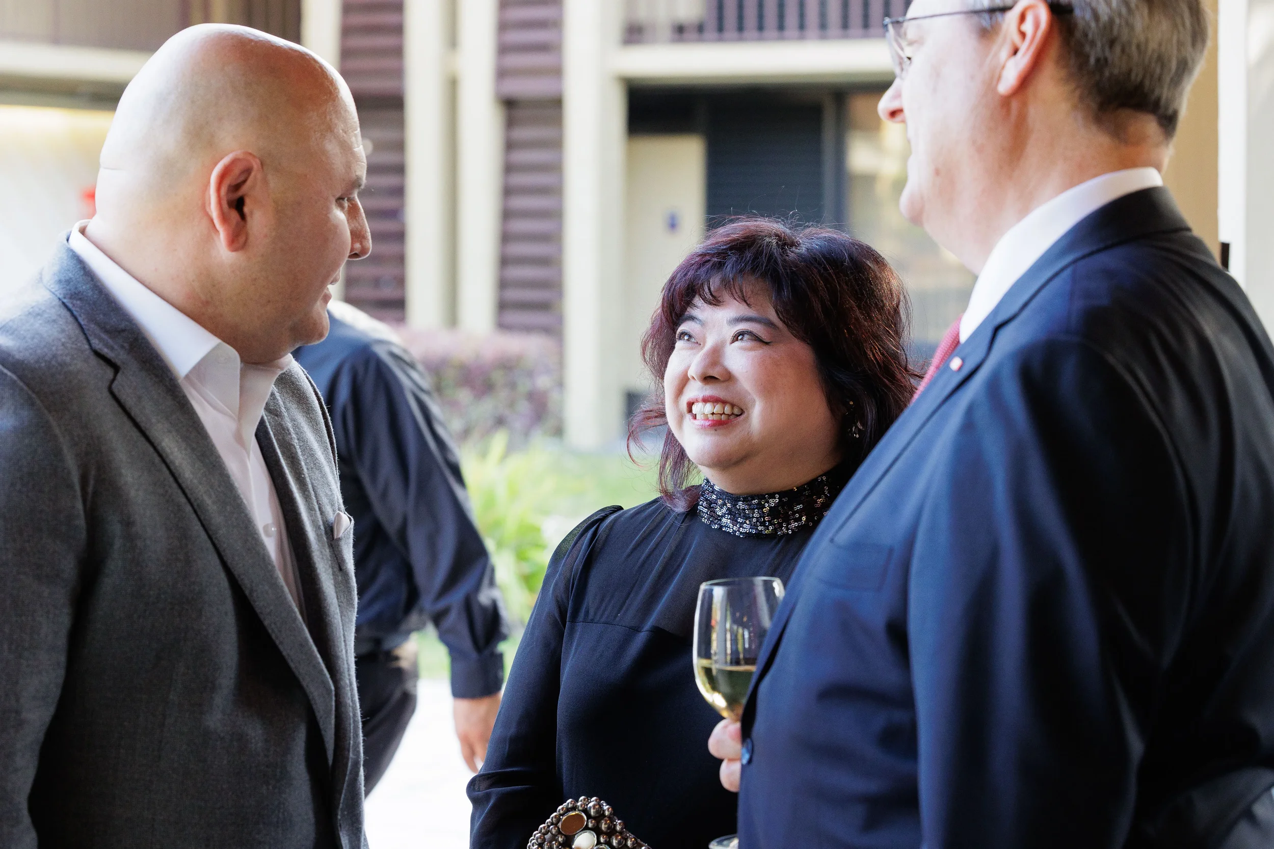Three attendees smile and converse over wine at outdoor networking reception at Orlando corporate event
