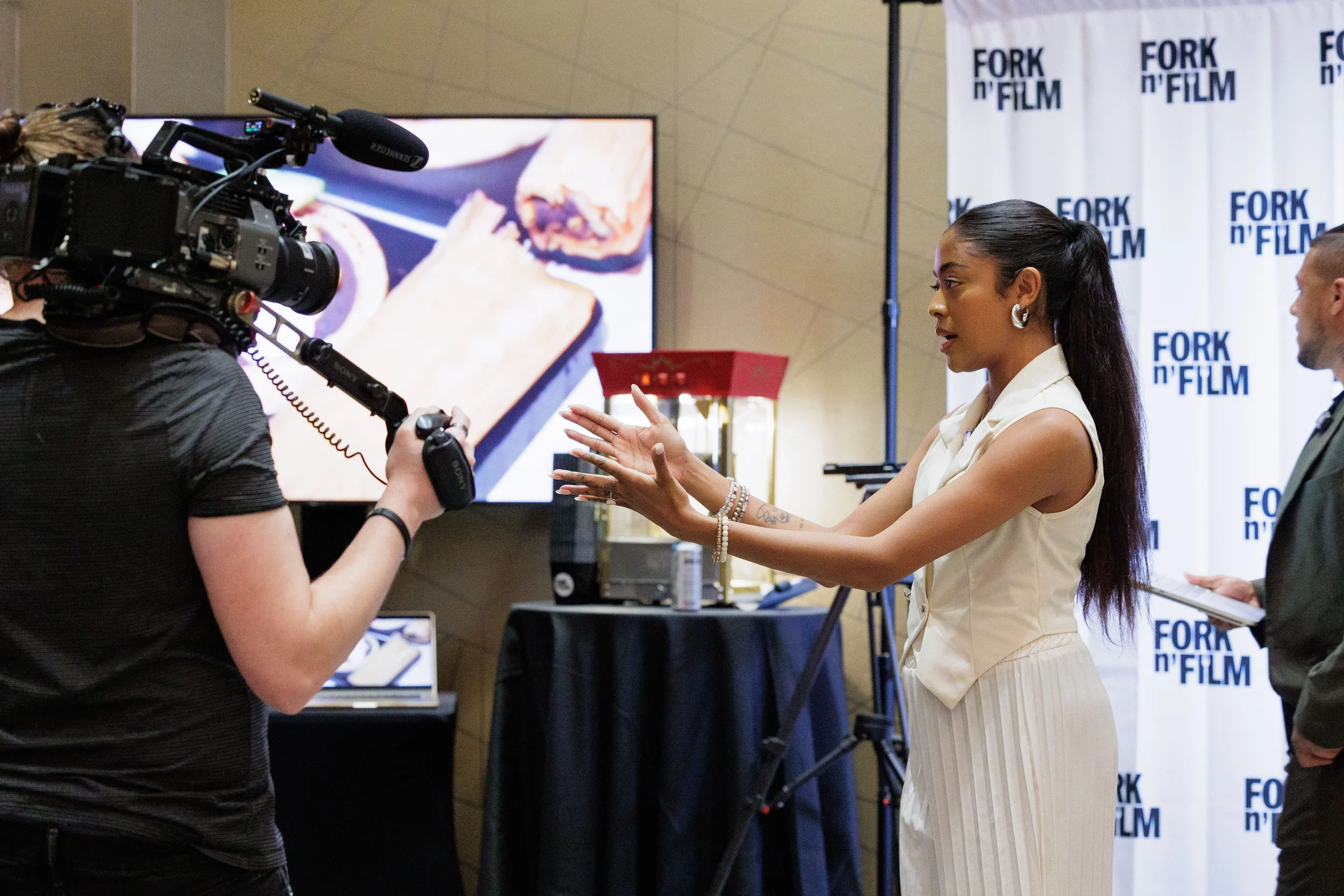 Female presenter gestures expressively before video camera at sponsor step-and-repeat at Chicago corporate event