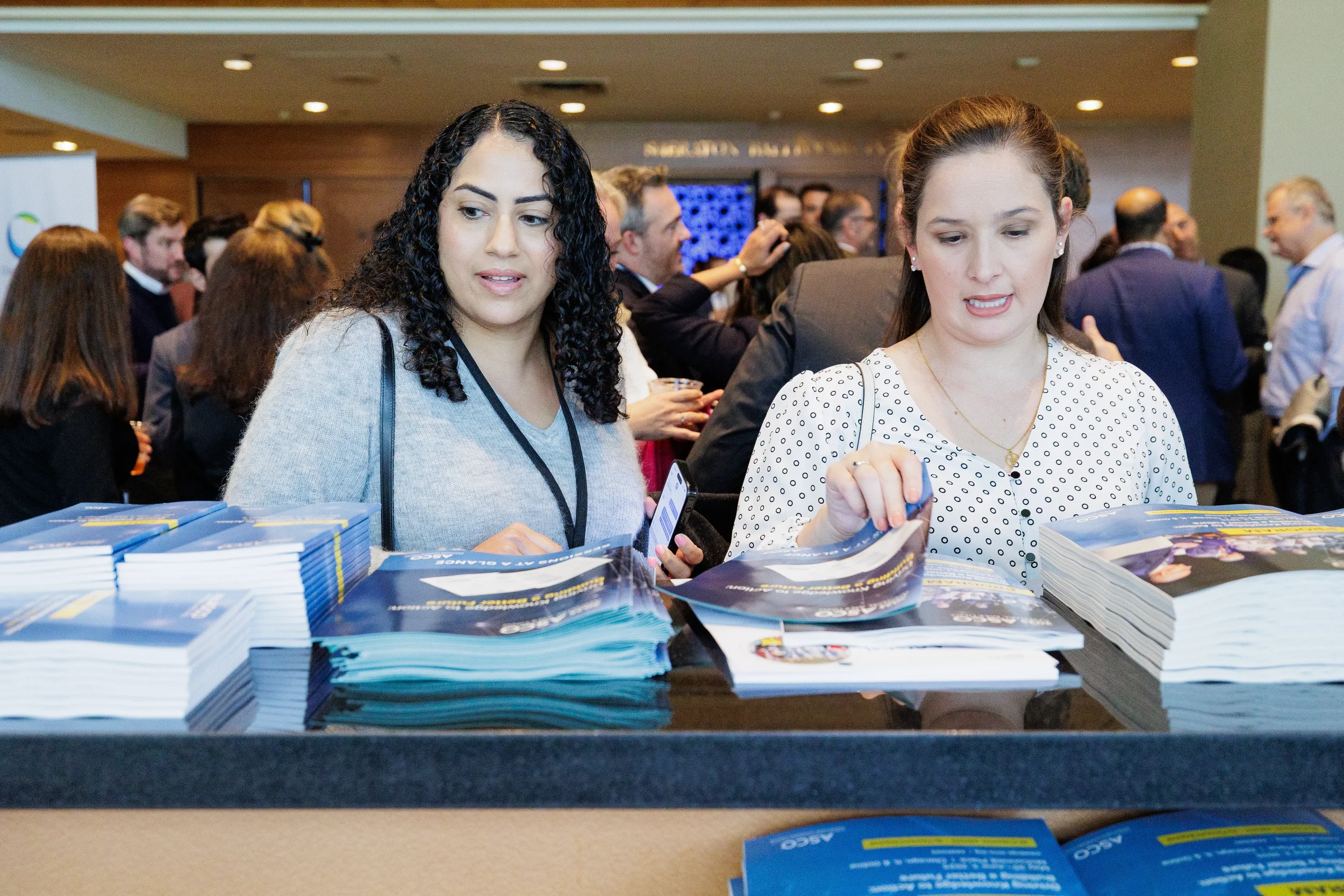 Attendees review conference program materials at registration table in Orlando