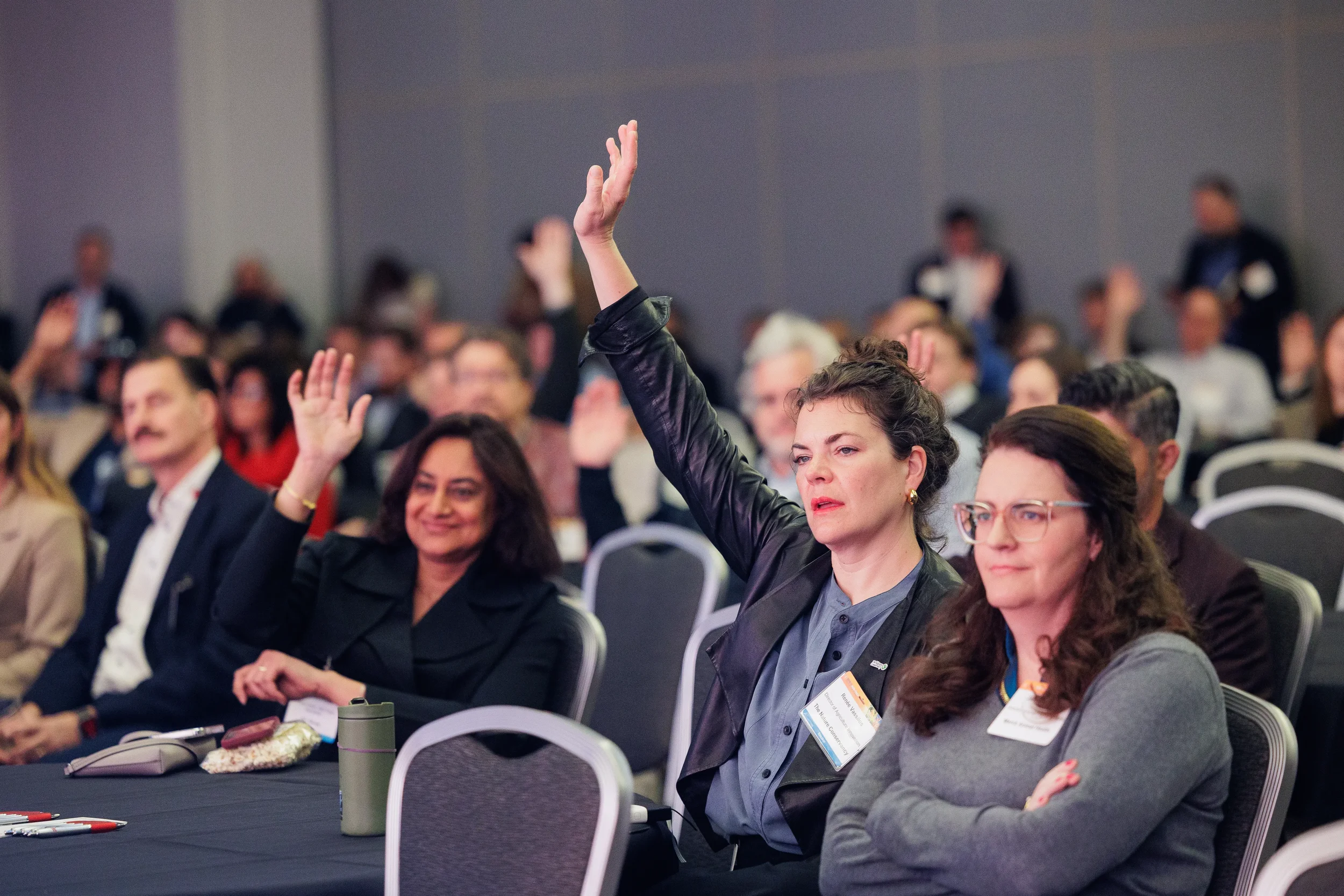 Attendee with name badge raises hand during interactive session at Chicago corporate industry conference