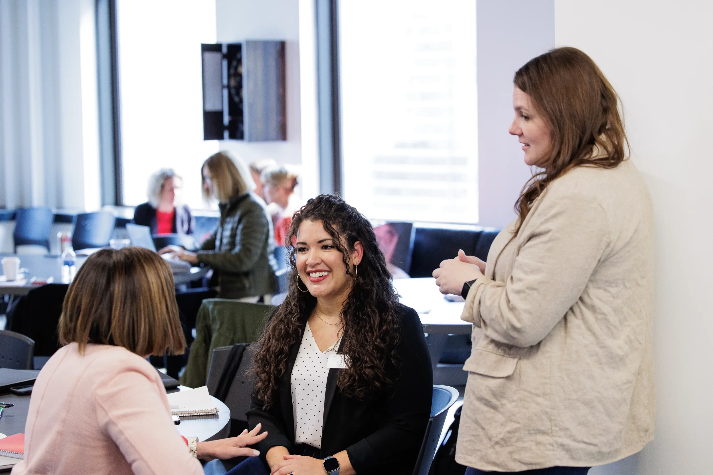 Three female attendees share an animated conversation at tables during Chicago corporate event networking