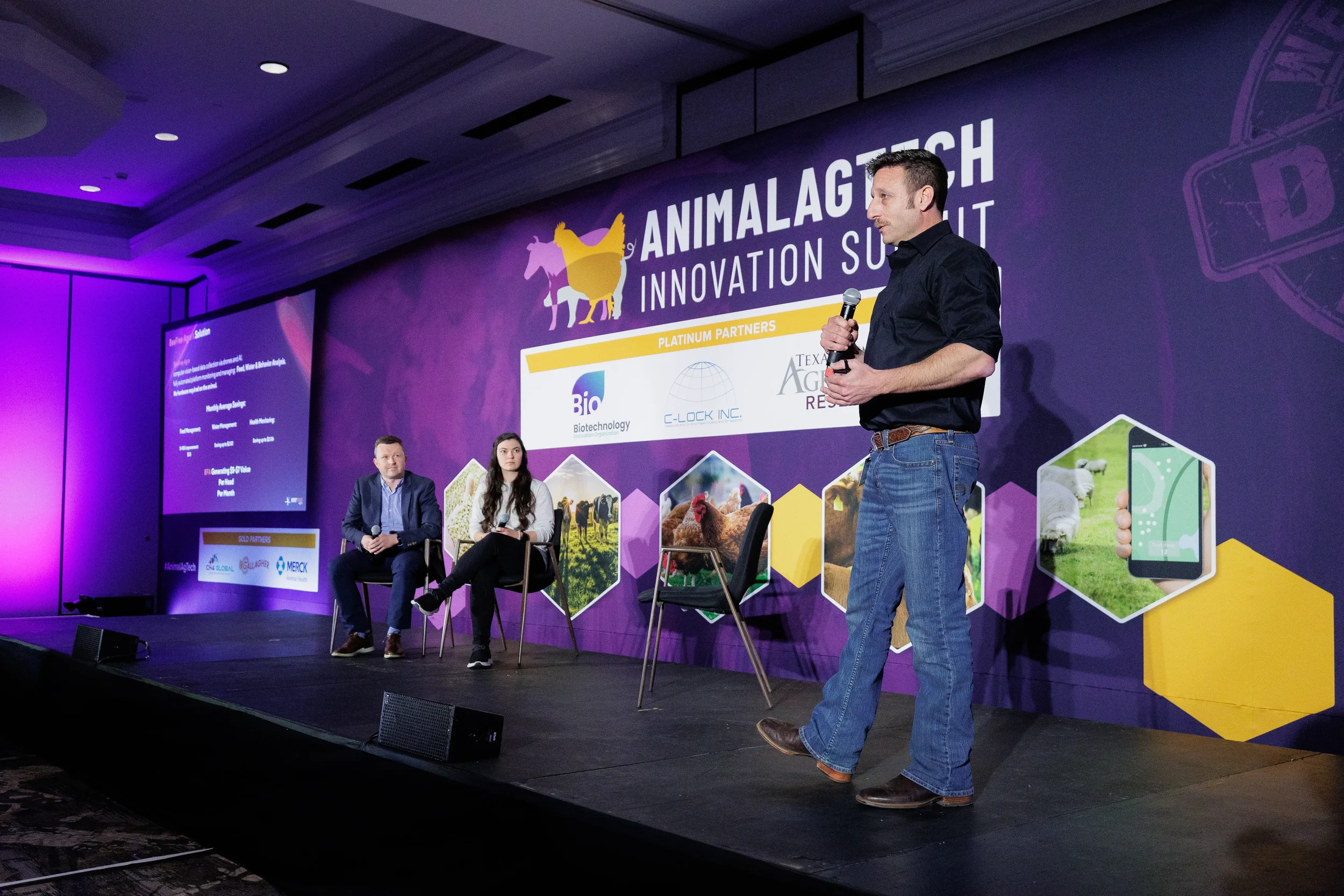 Speaker stands and presents on stage before full event banner at Chicago industry conference
