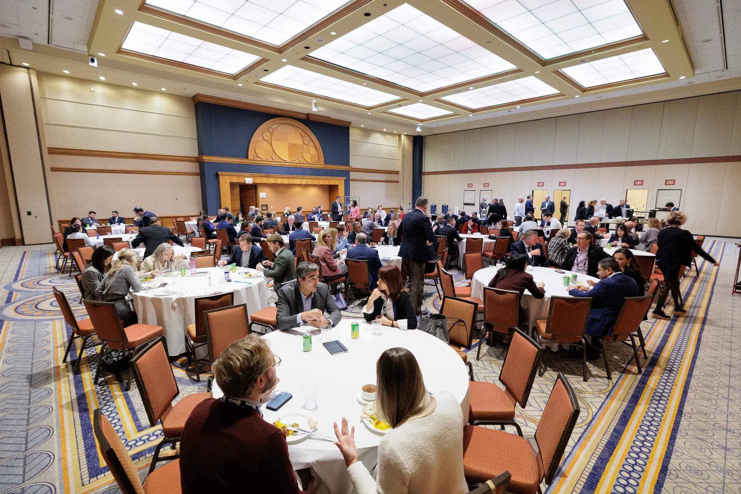 Conference attendees network over lunch at round tables in Orlando hotel ballroom