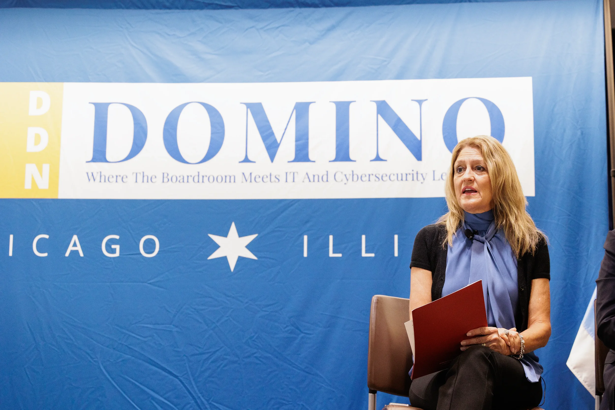 Moderator seated on stage in front of branded backdrop during Chicago industry conference panel discussion