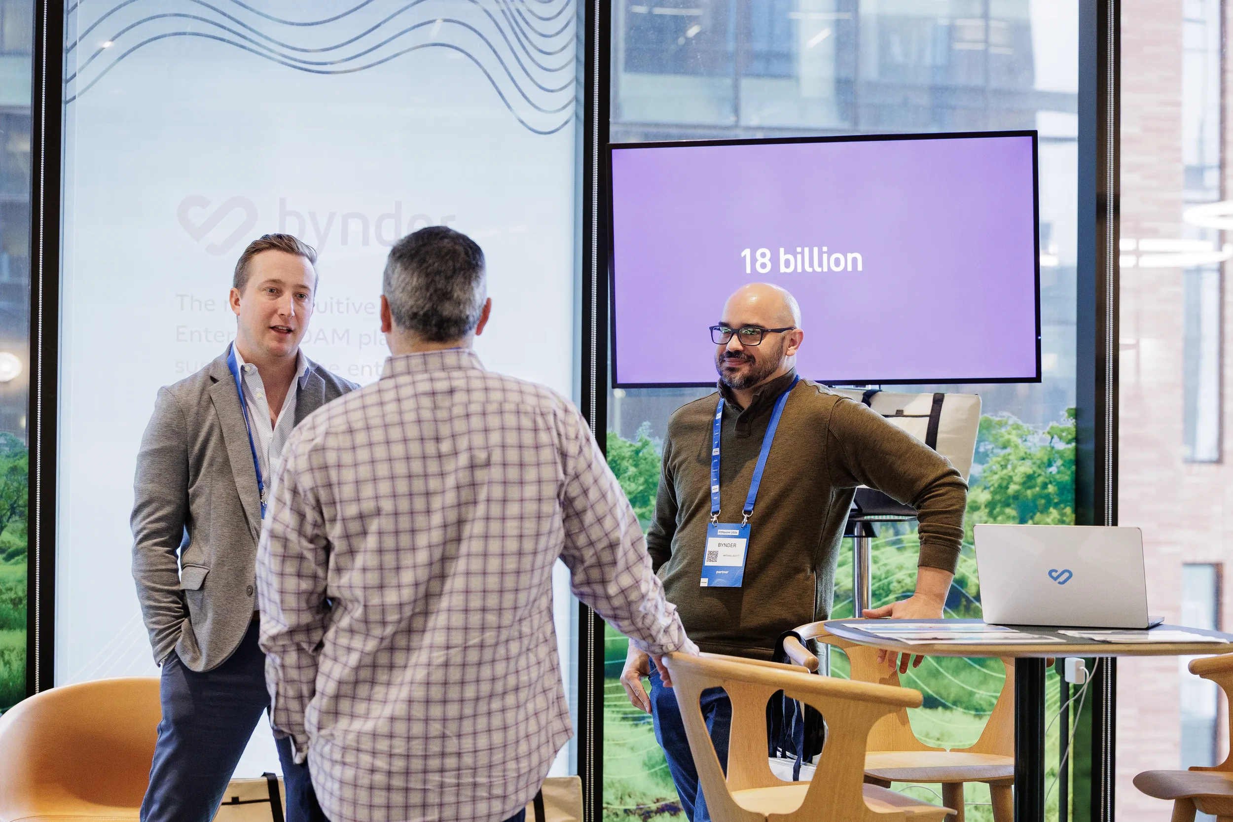 Attendees talk with exhibitor at booth beside purple display screen during Chicago corporate trade show