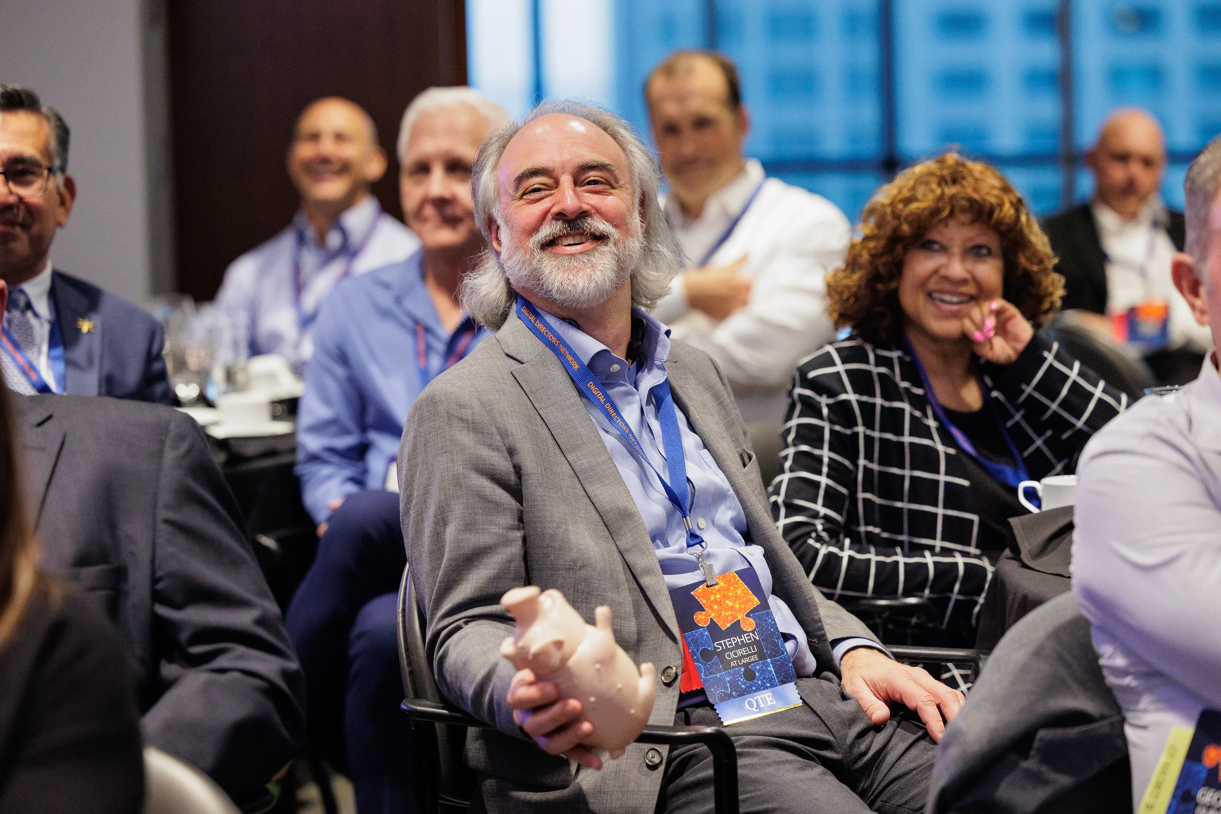 Male attendee with lanyard laughs warmly while seated at Chicago corporate conference evening event