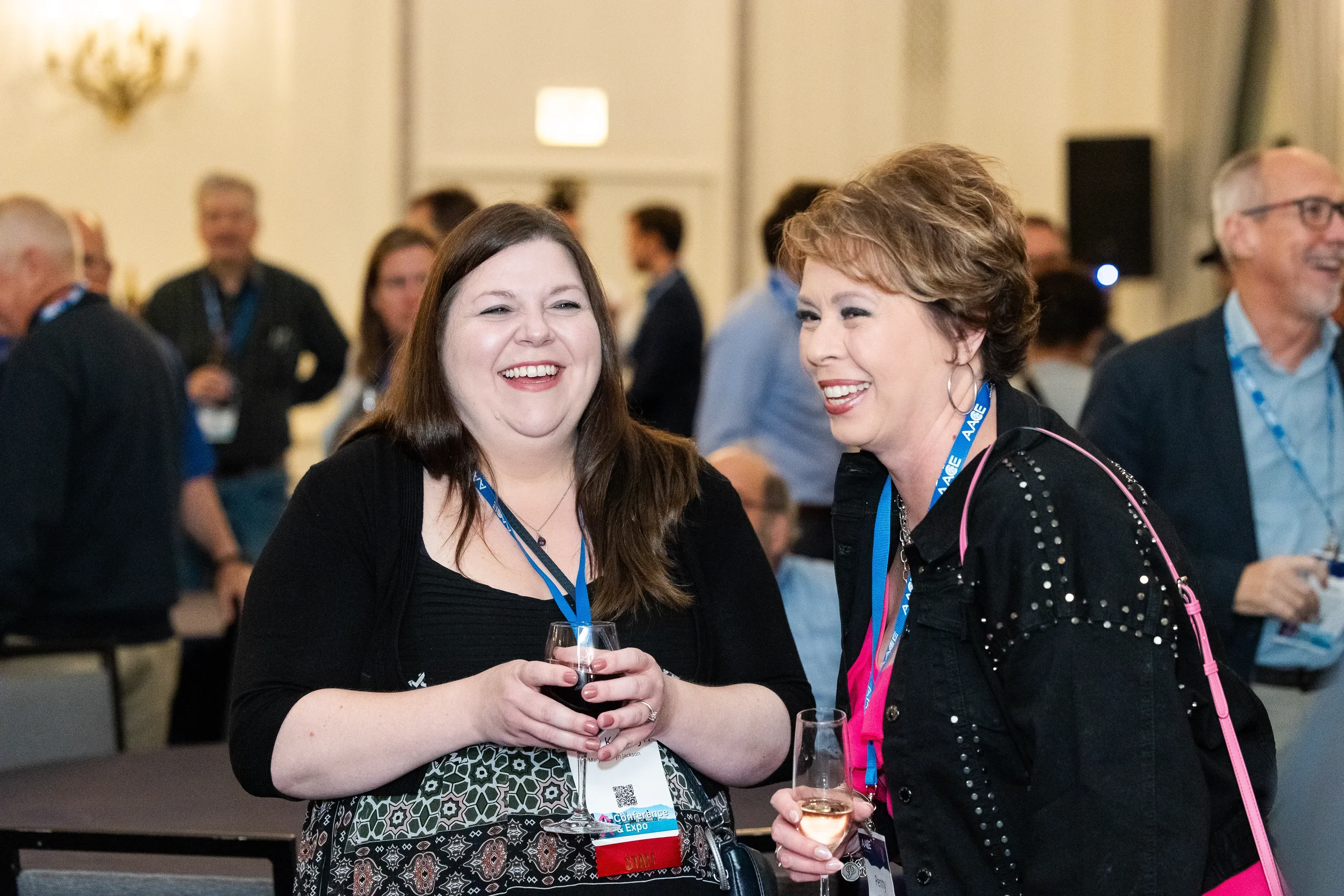 Two attendees laugh together while holding wine glasses during reception at Chicago corporate conference