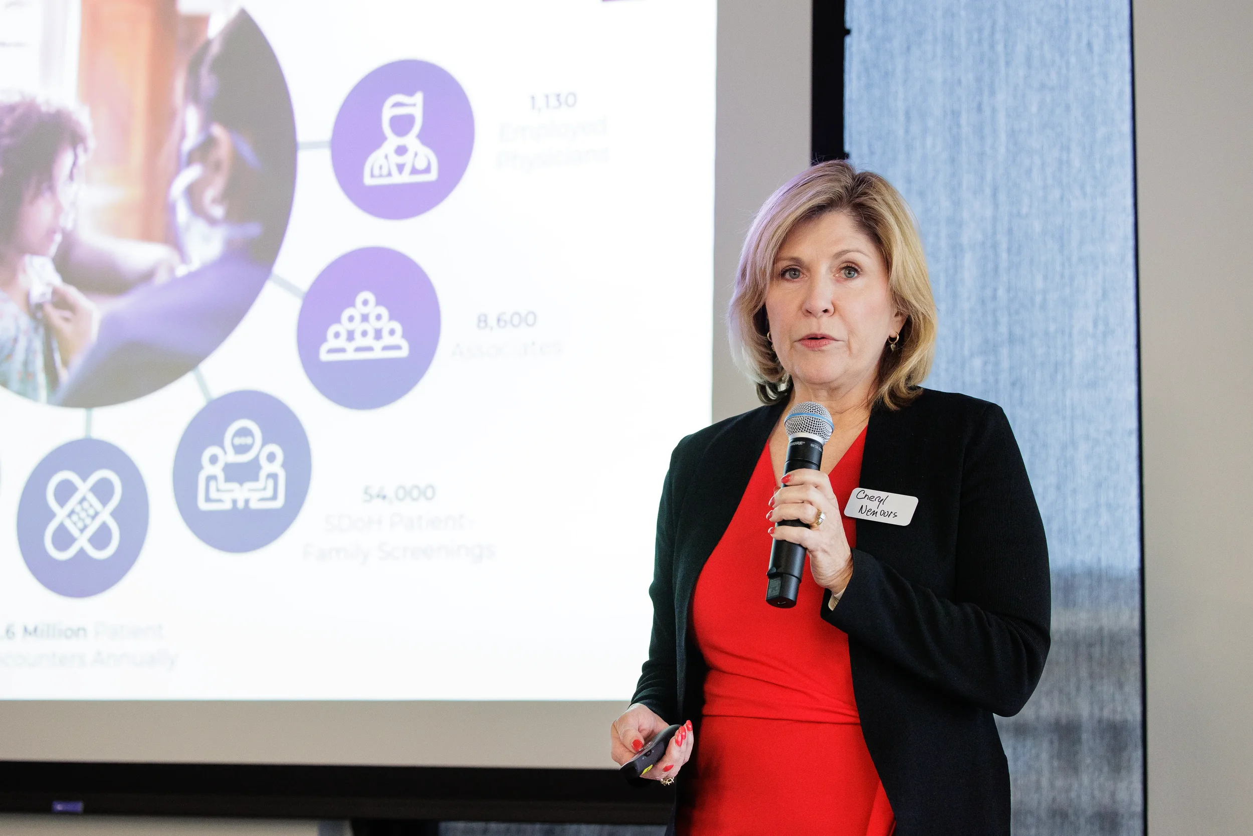 Female speaker presents with microphone beside a data-filled projection slide at Chicago industry conference