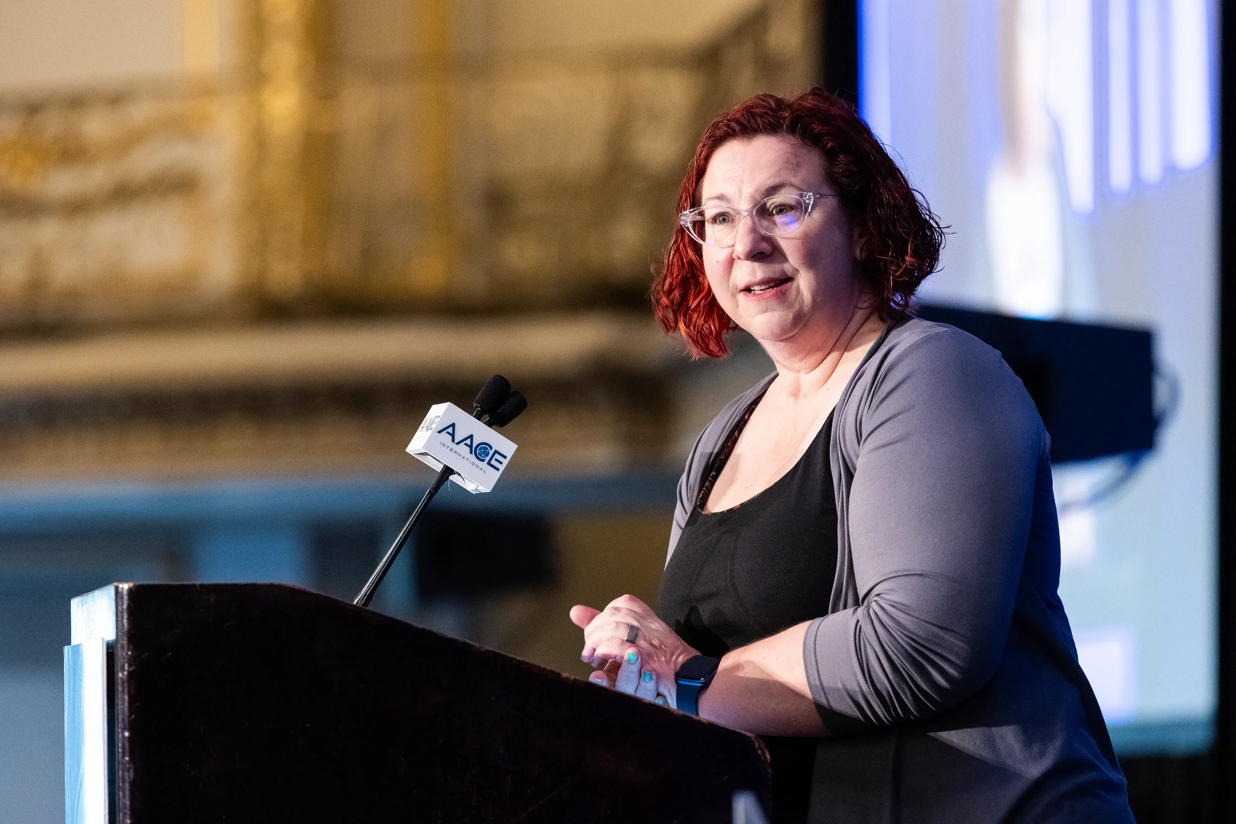 Speaker addresses audience from branded podium in ornate ballroom at Orlando industry conference