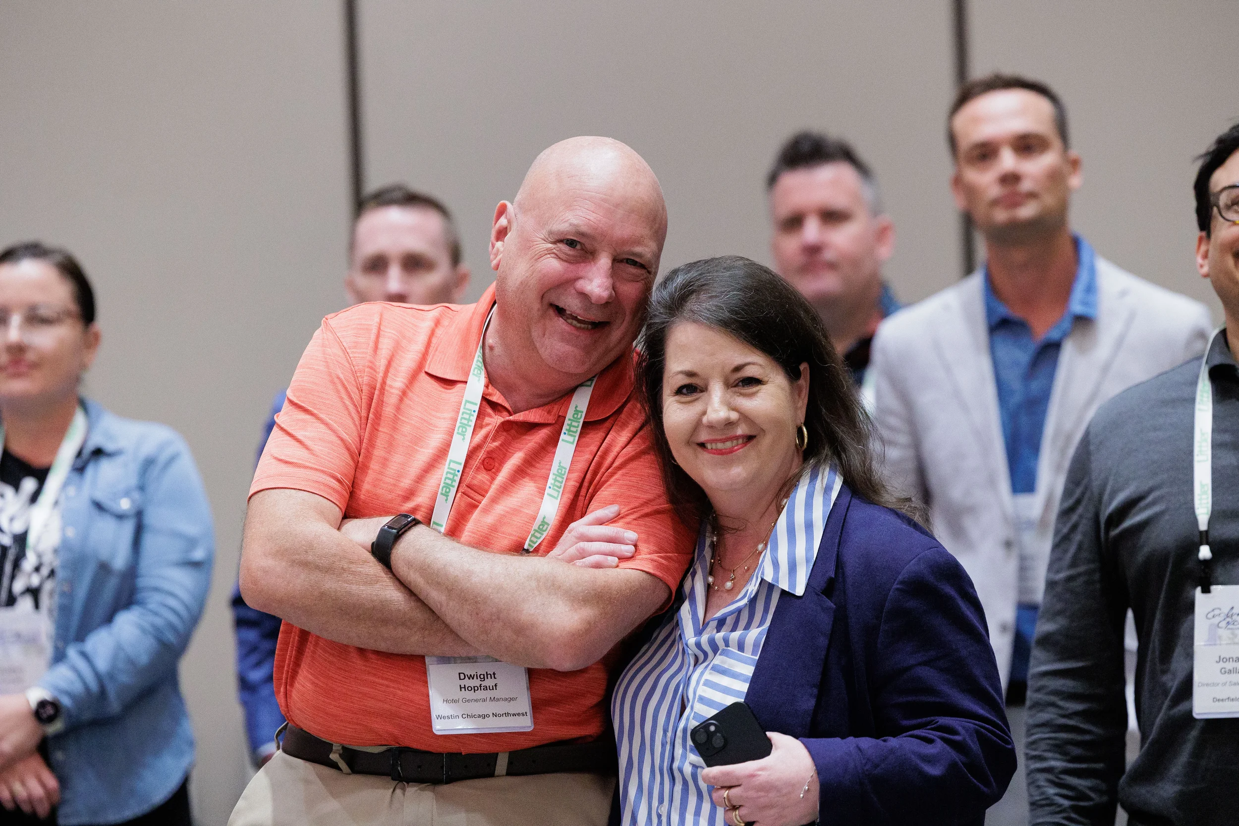 Two attendees with lanyards pose and smile together among group at Orlando corporate conference