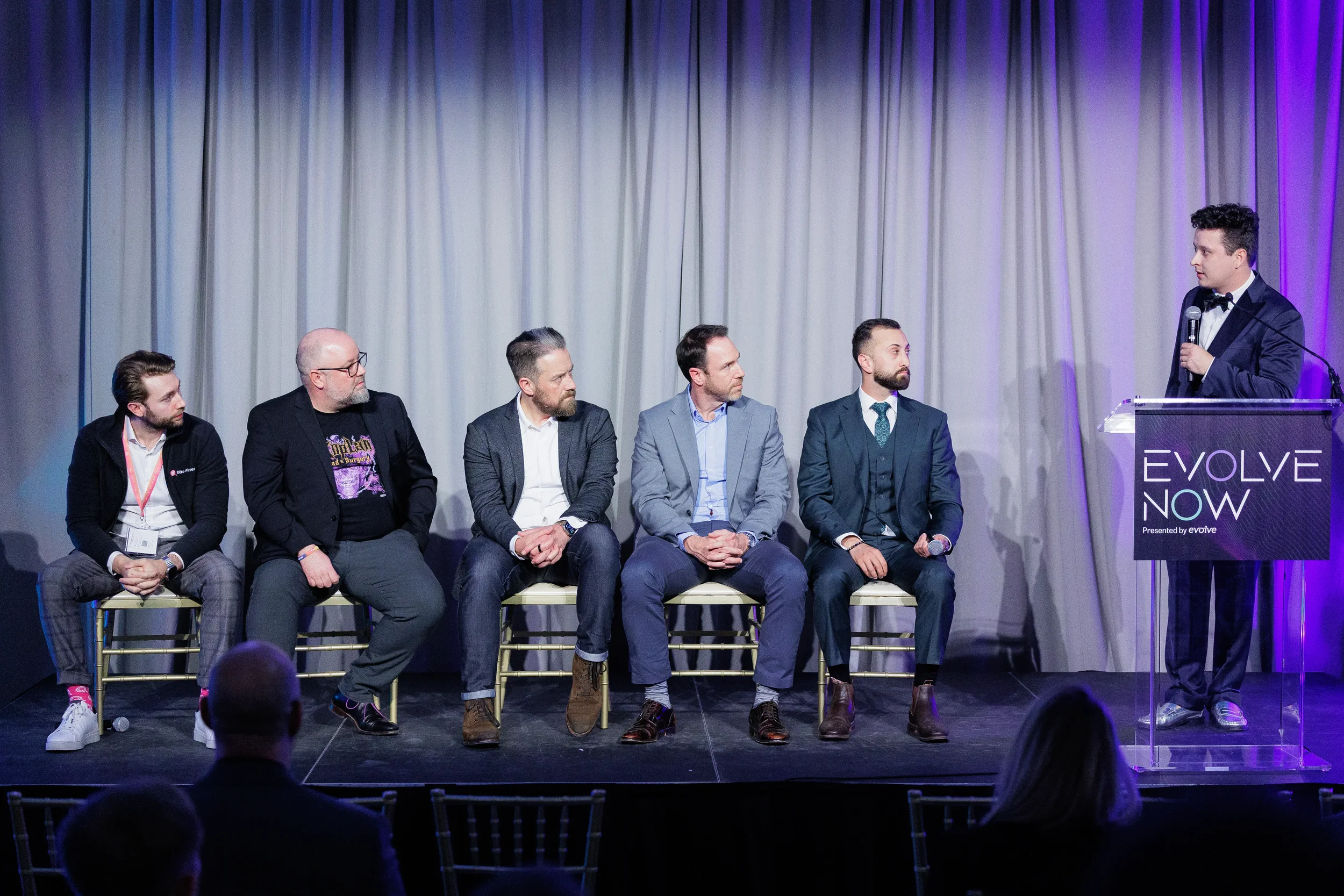 Five panelists seated on stage with moderator at podium during Orlando industry conference
