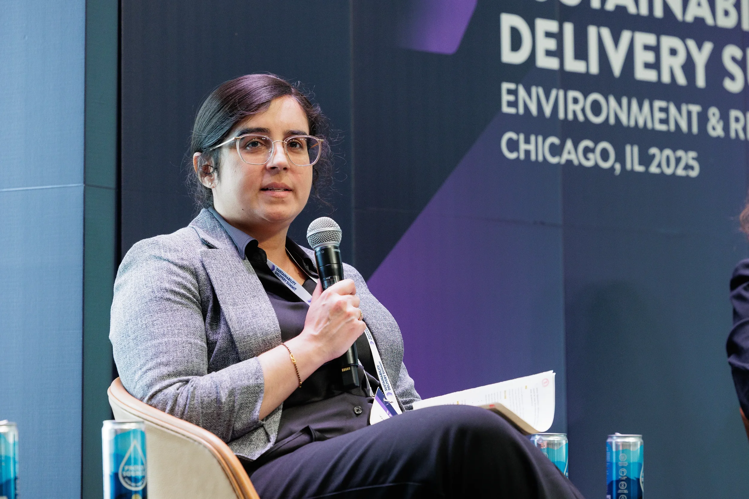 Panelist speaks into microphone with branded conference backdrop at Chicago industry summit