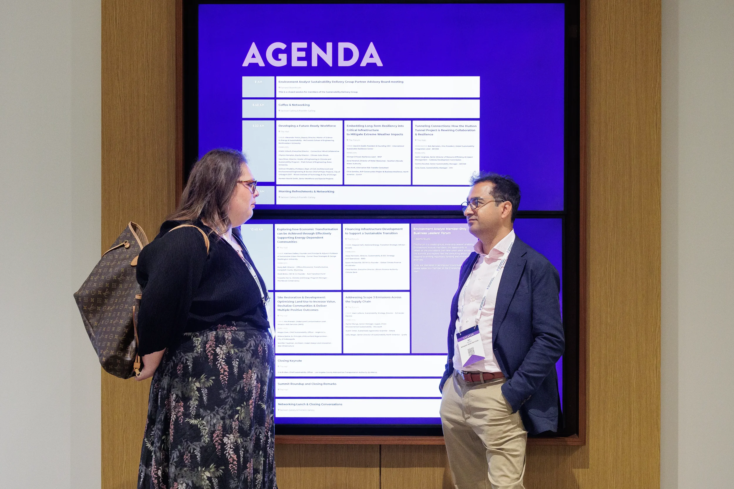 Attendees converse in front of agenda screen during Chicago industry conference